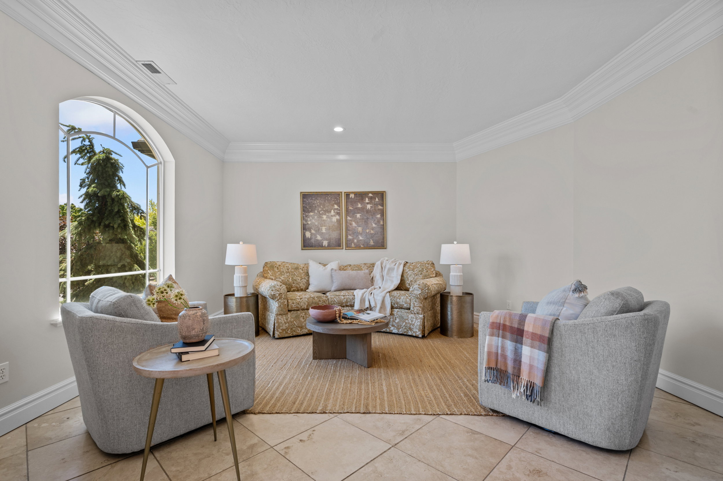 Spacious room featuring an arched window, crown molding