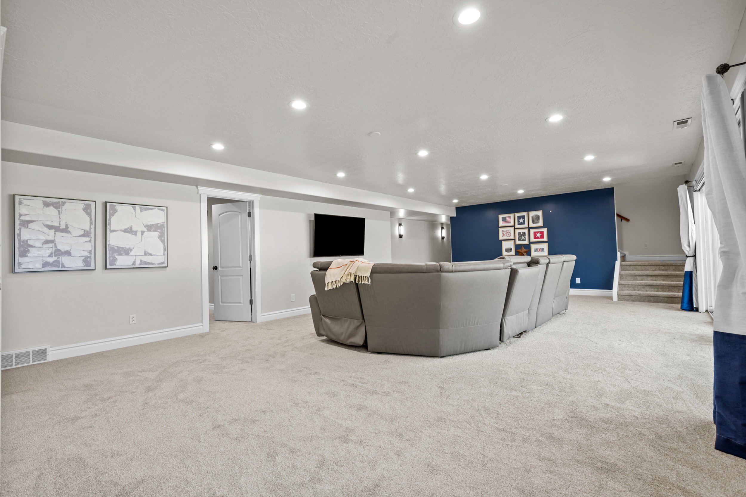 Spacious room featuring light-colored carpeting, recessed lighting, and a prominent accent wall