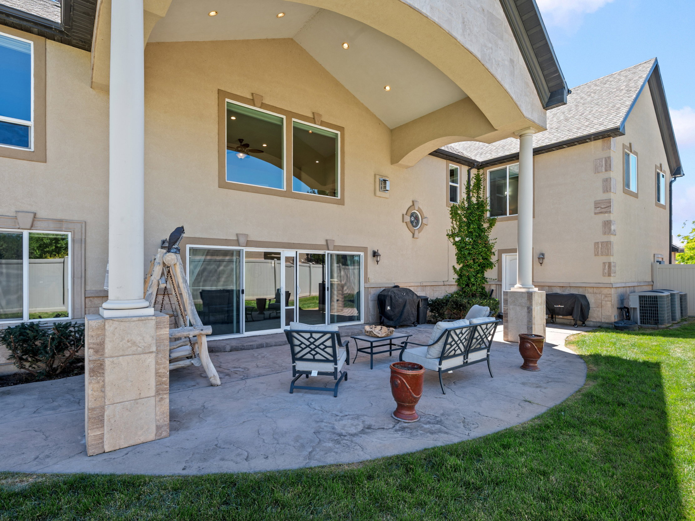 Expansive stamped concrete patio featuring a covered area with recessed lighting and structural columns