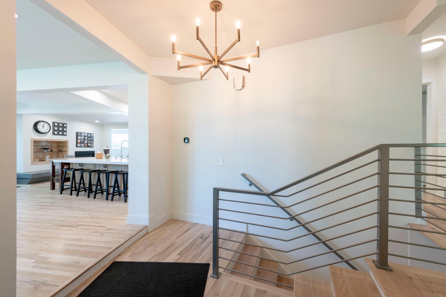 Entryway featuring a modern chandelier, light wood-finish flooring, and a contemporary metal railing staircase