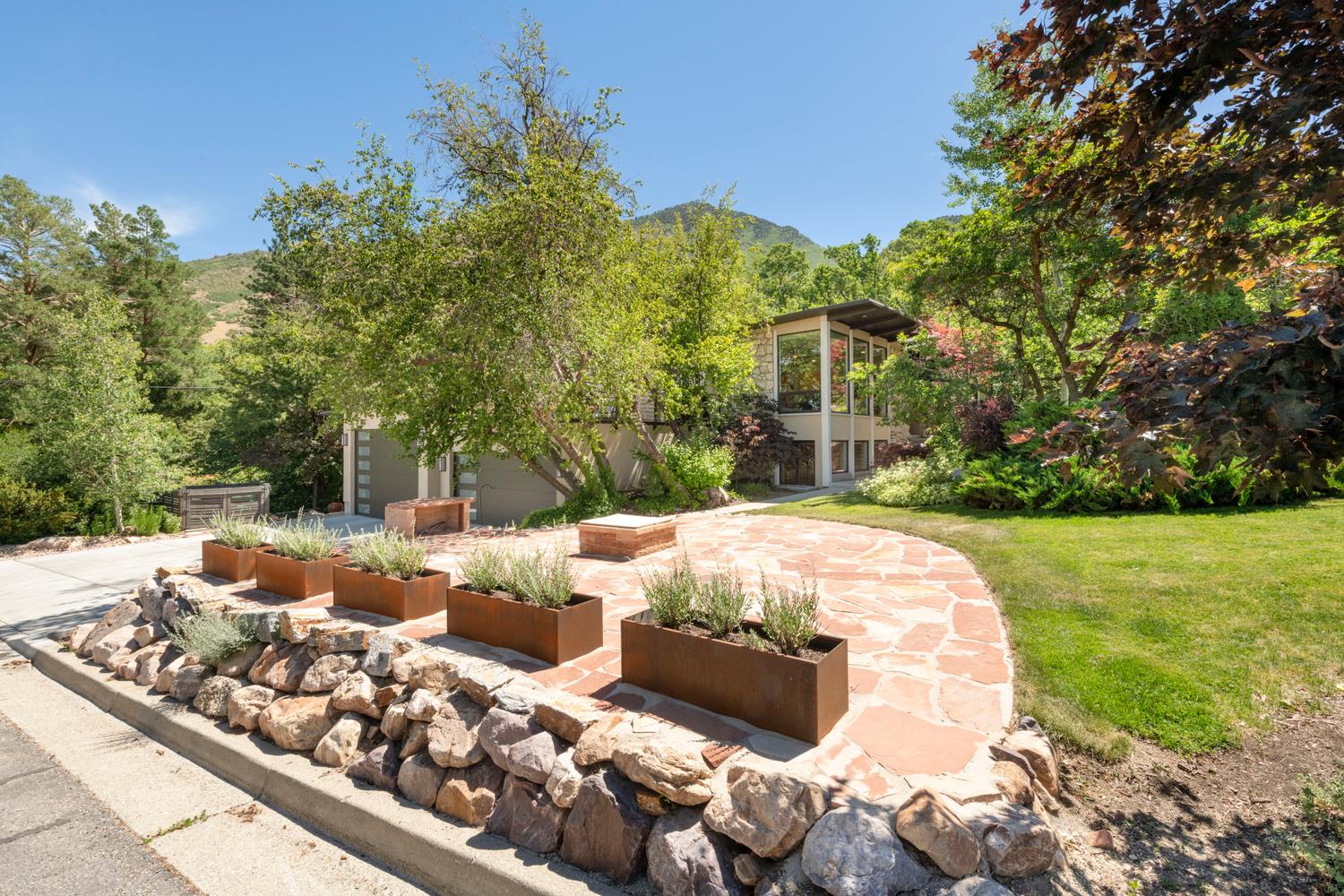 Stone paver pathway bordered by a rock retaining wall and planter boxes
