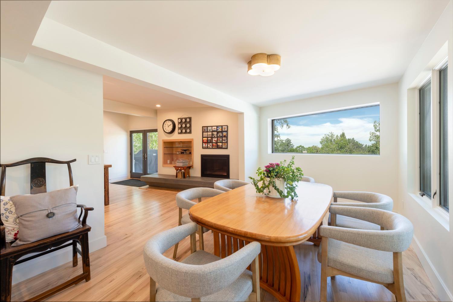 Dining area with wood-finish flooring, a contemporary ceiling light fixture, and a large horizontal window providing natural light