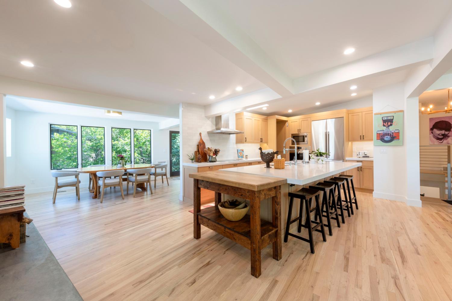 Open-concept kitchen and dining area featuring light wood-finish flooring, recessed lighting, and a large central island with seating