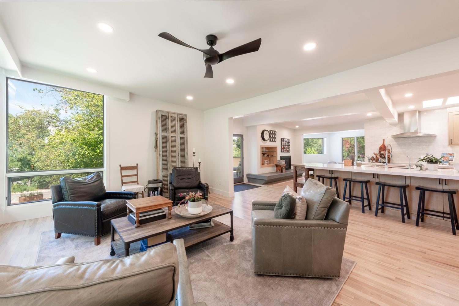 Light wood-finish flooring throughout, featuring recessed lighting and a modern ceiling fan