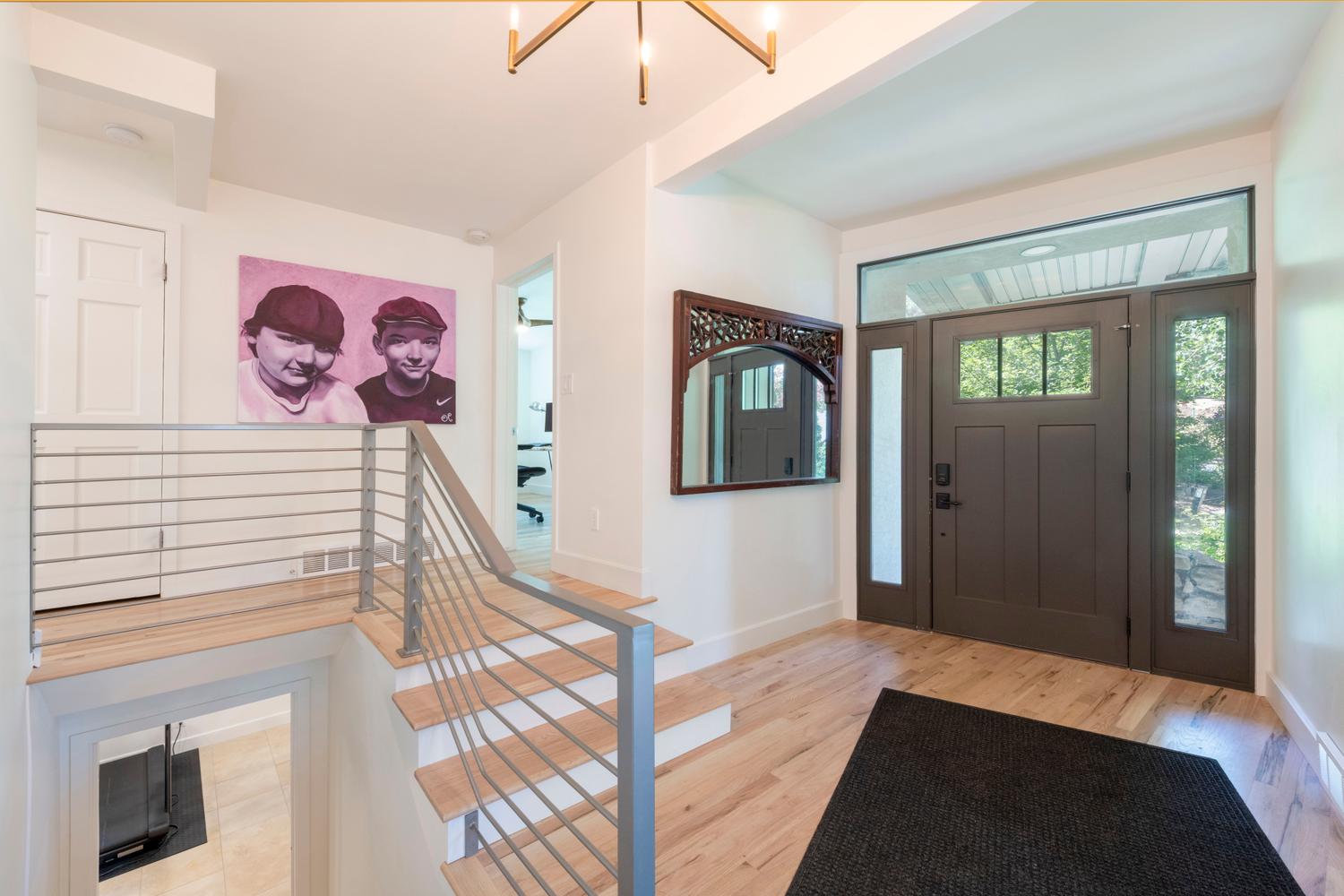 Entryway featuring wood-finish flooring, a contemporary chandelier, and a dark-paneled front door with sidelights and transom window