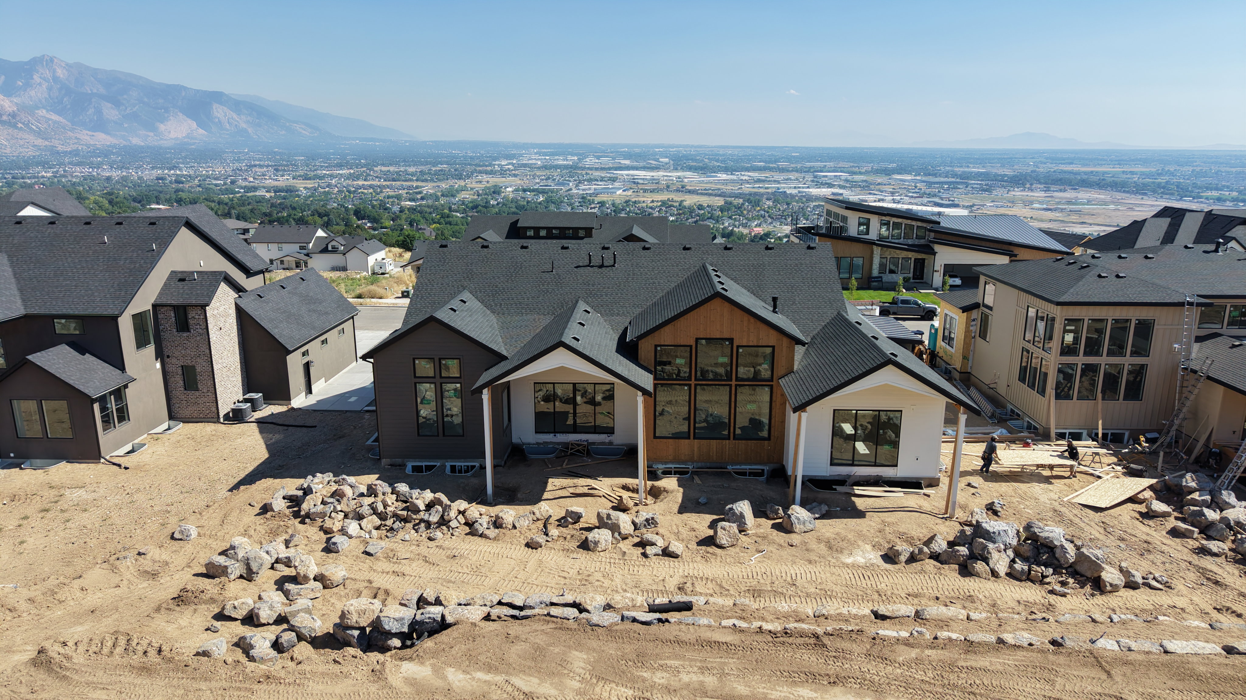 Modern residence featuring a dark gray roof, wood-tone siding accents, and expansive windows