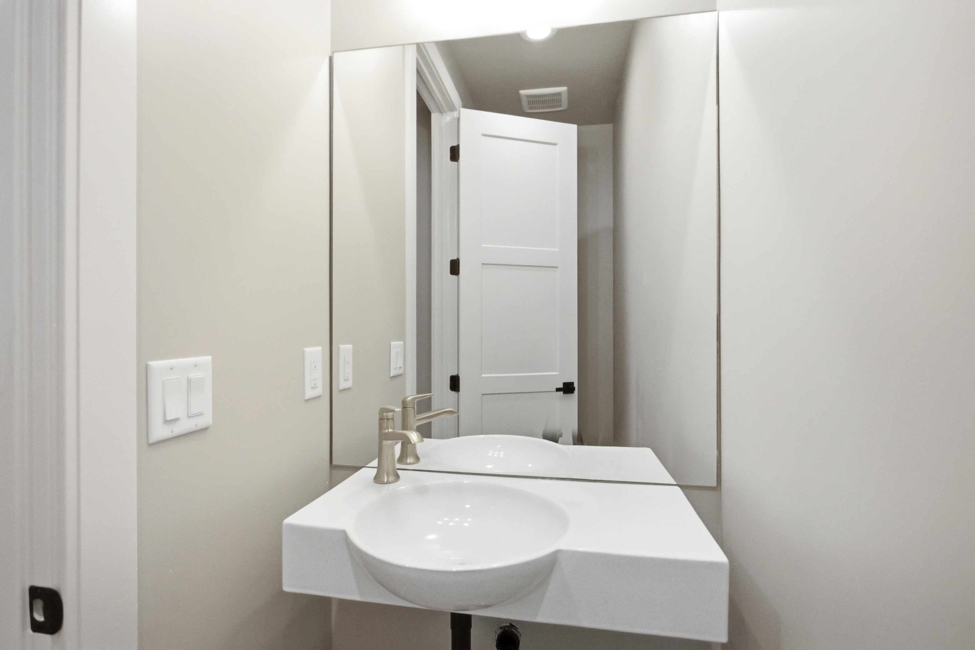 Modern half bathroom vanity featuring an integrated basin, brushed nickel faucet, and a large wall-mounted mirror
