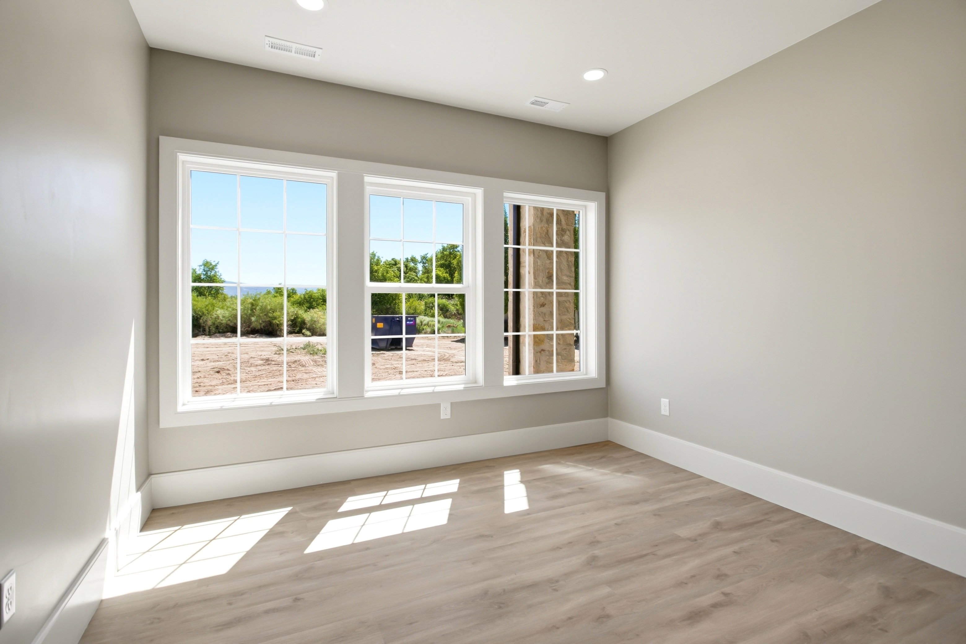 Bedroom featuring three large grid-pattern windows, recessed lighting, and neutral wall tones
