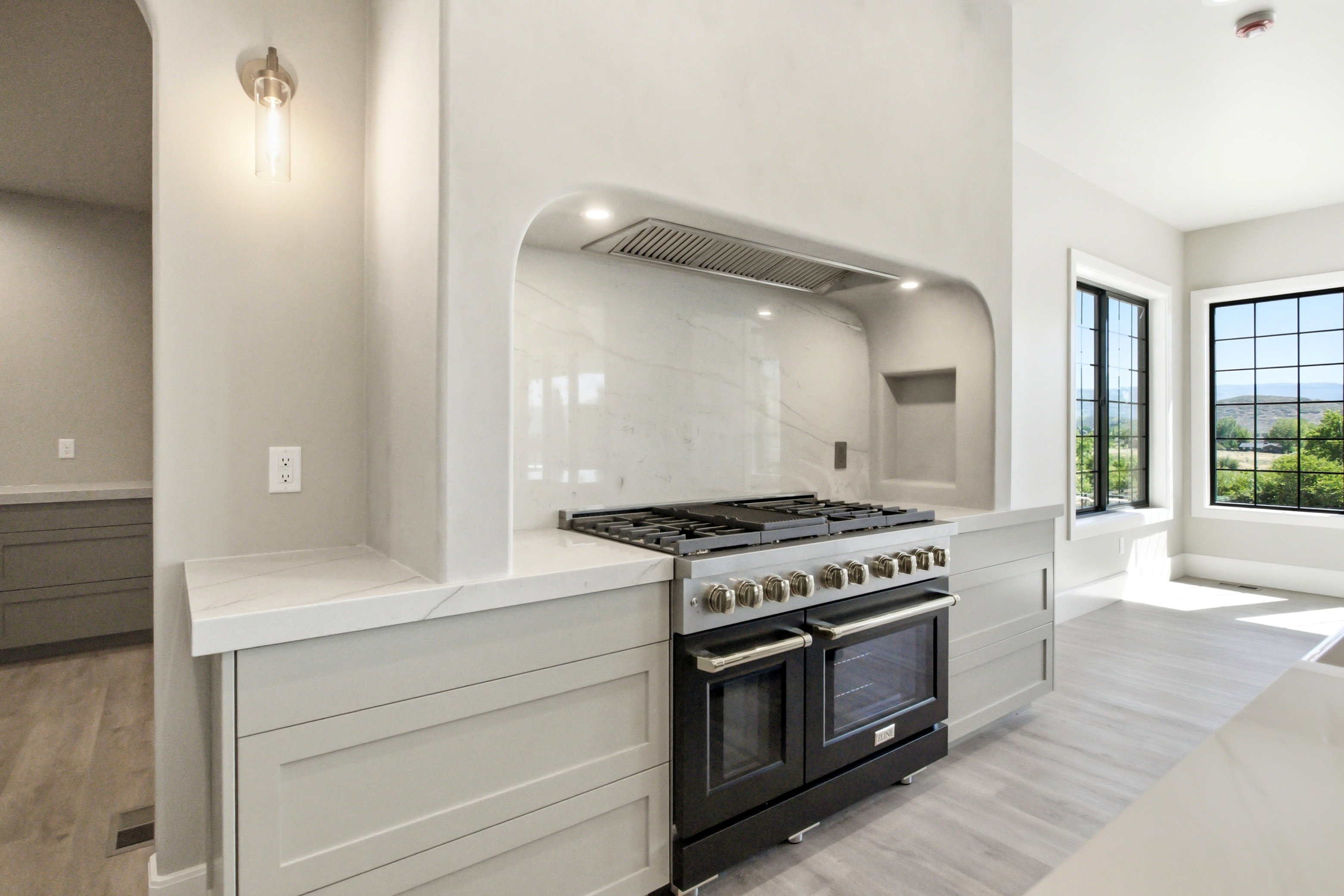 Professional-grade range with stainless steel hardware, set within an arched alcove with a tile backsplash