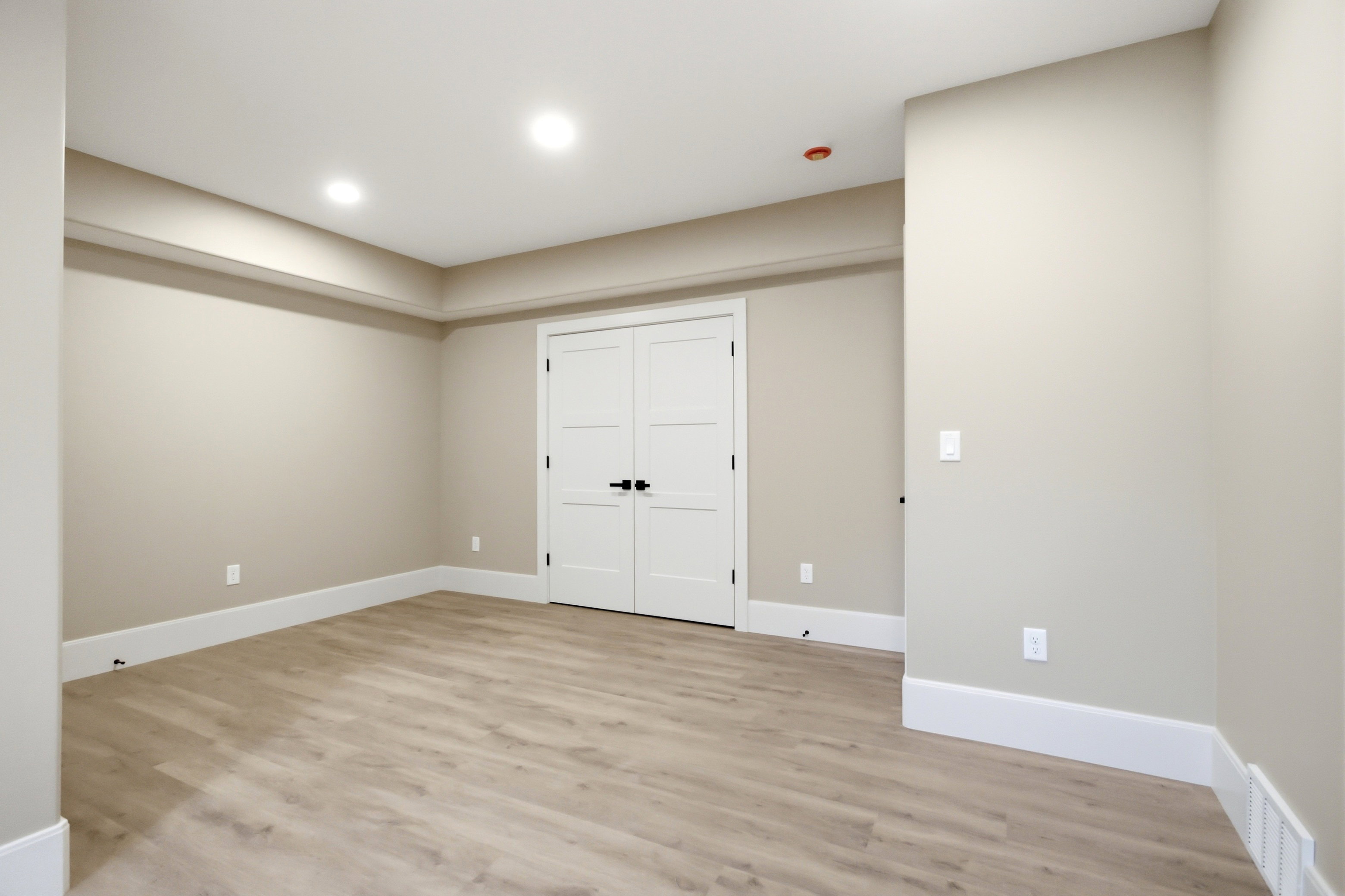 Spacious room featuring light wood-finish flooring, recessed lighting, and a neutral wall palette