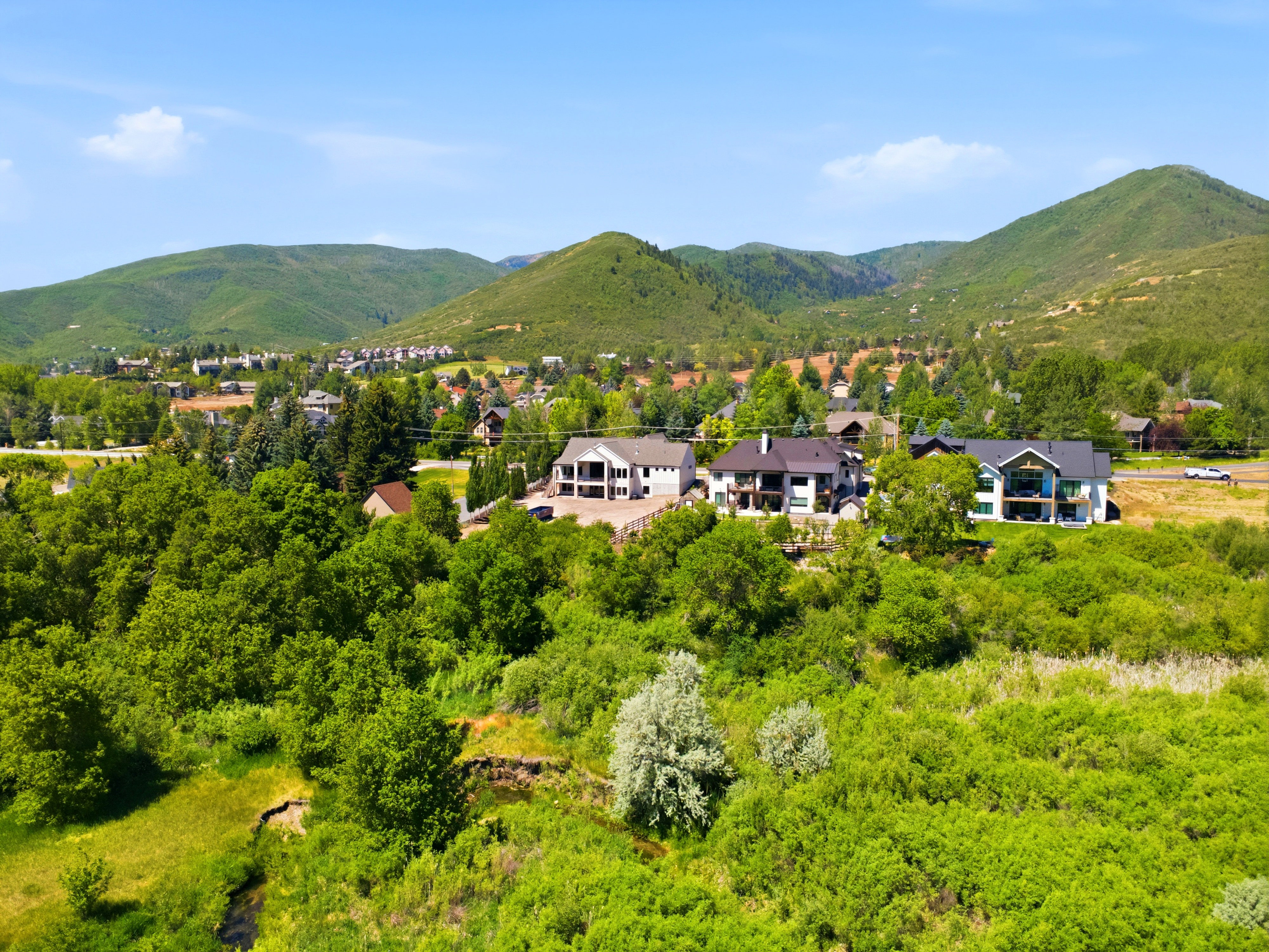 Lush green landscape  and back of home featuring a natural waterway and distant mountain ranges