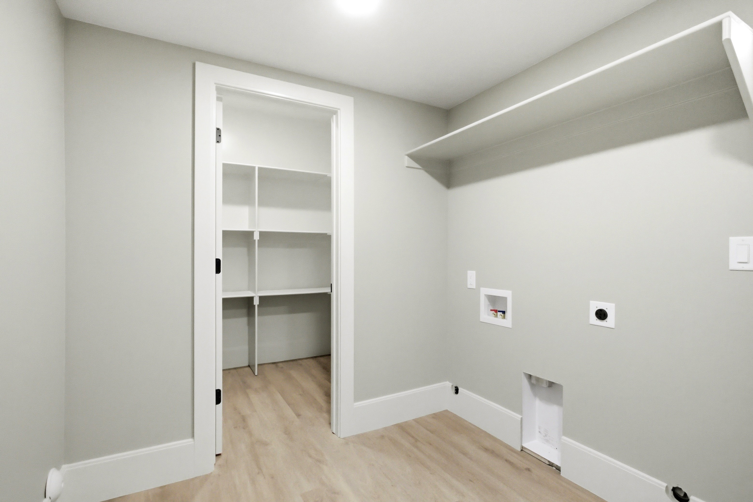 Utility room featuring a built-in shelf, and a pantry with white shelving