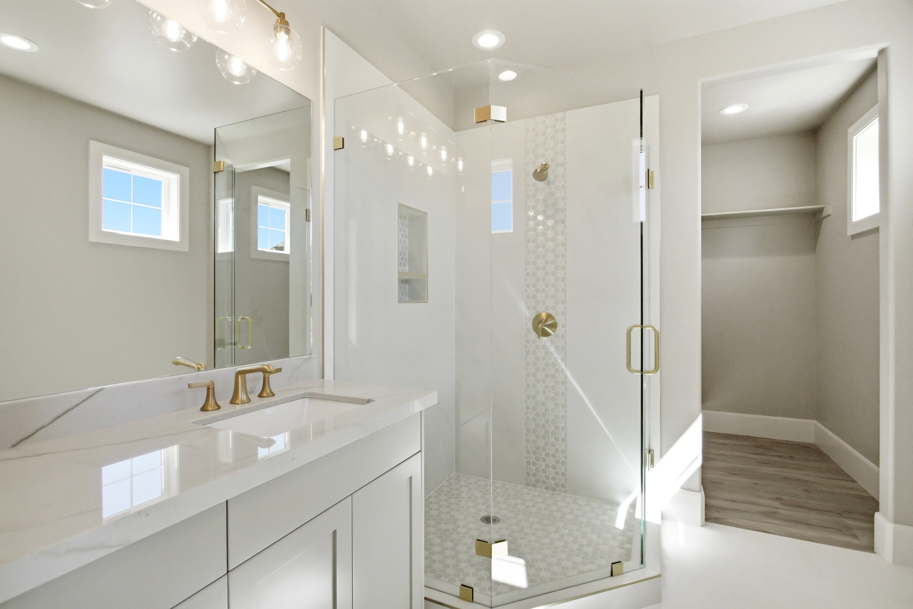 Modern bathroom featuring a single vanity with stone-finish countertop, undermount sink, and brass-finish faucet