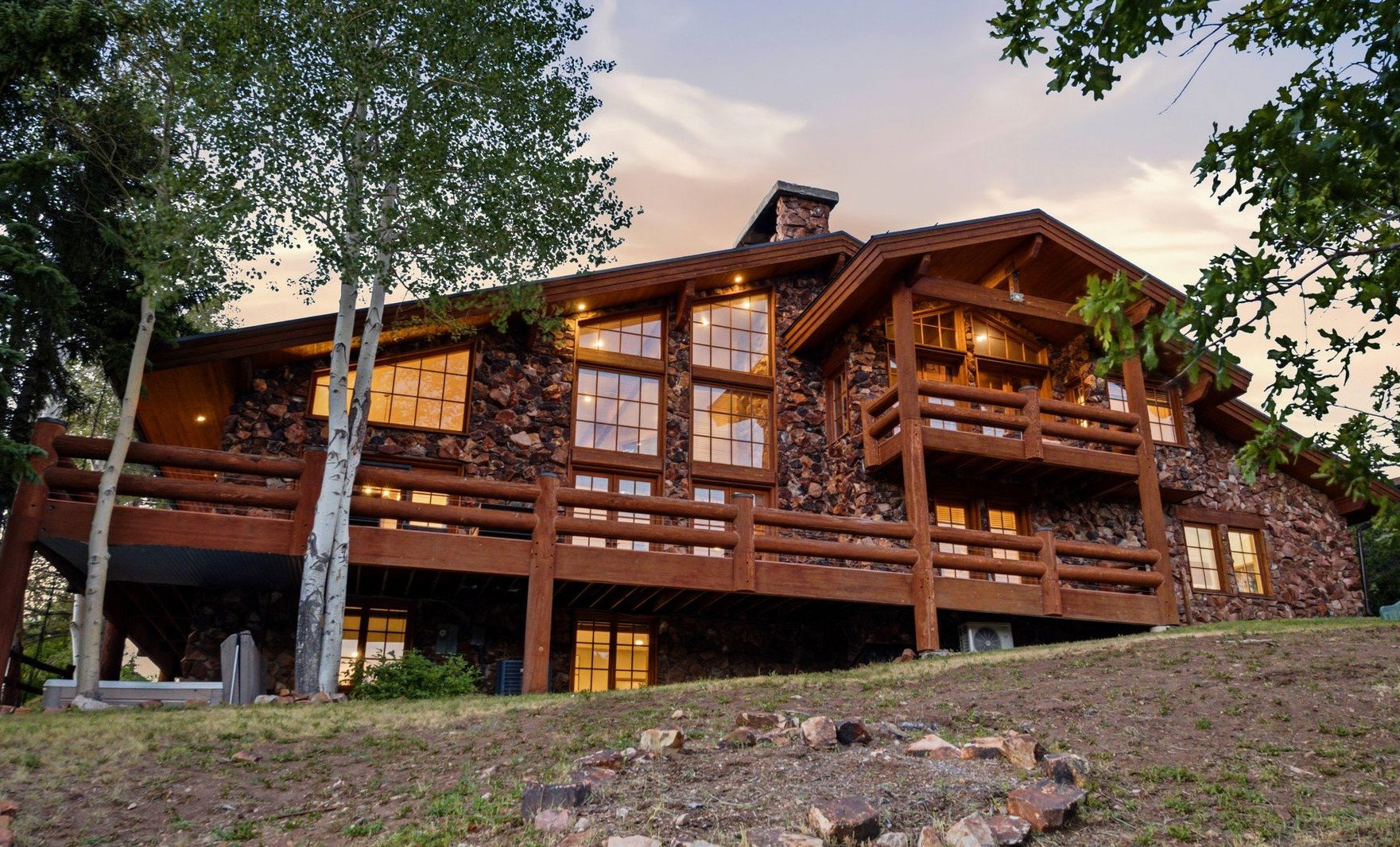 Stone and log exterior architecture featuring multiple balconies and expansive window walls