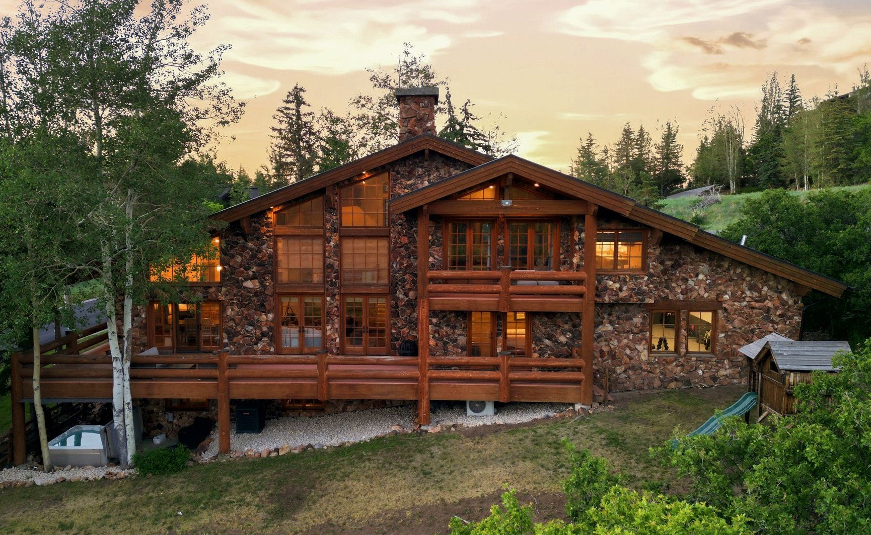 Stone-clad mountain home with extensive wood decking and multiple large windows