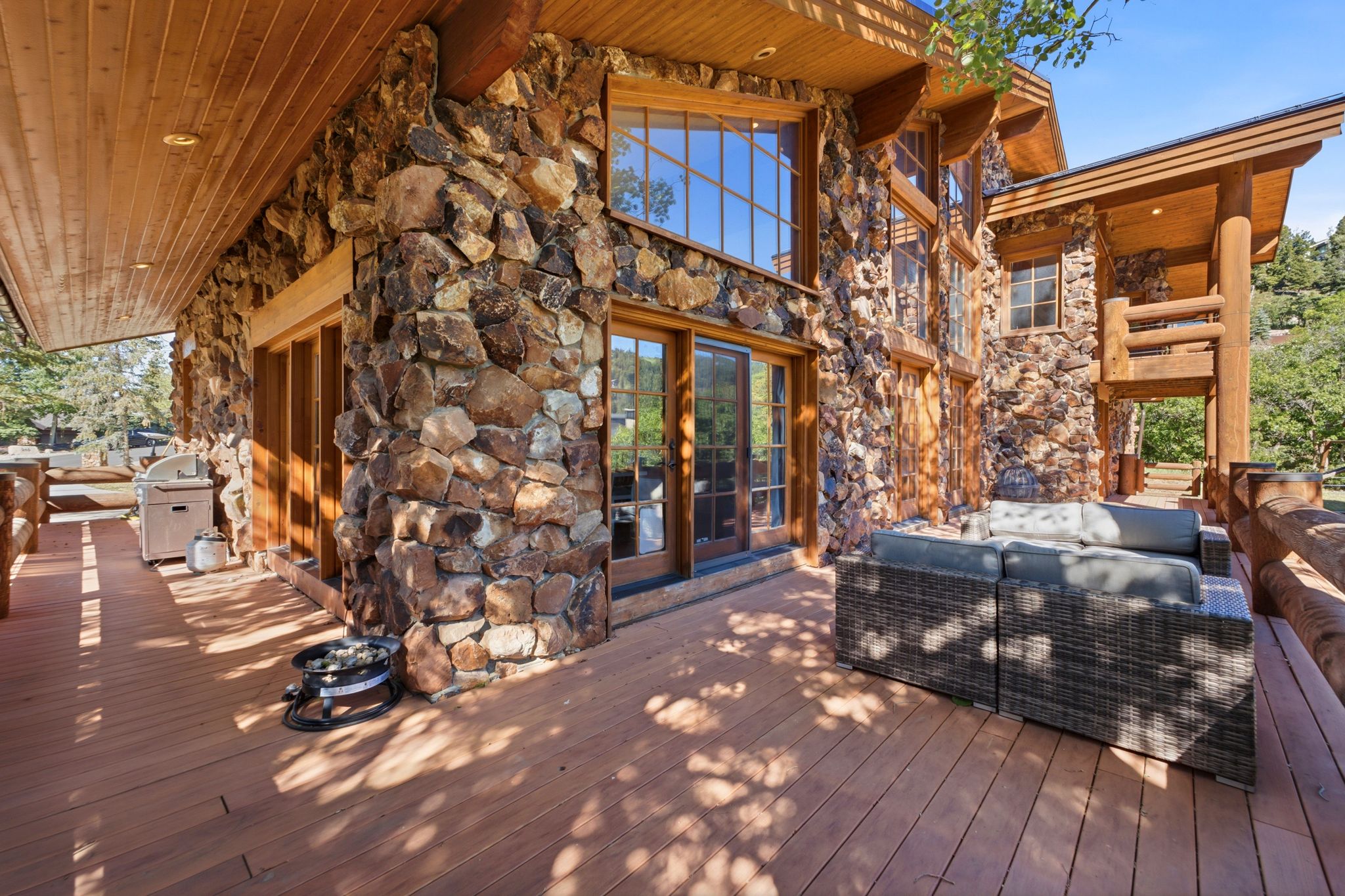 Expansive wood deck with natural stone and wood log exterior