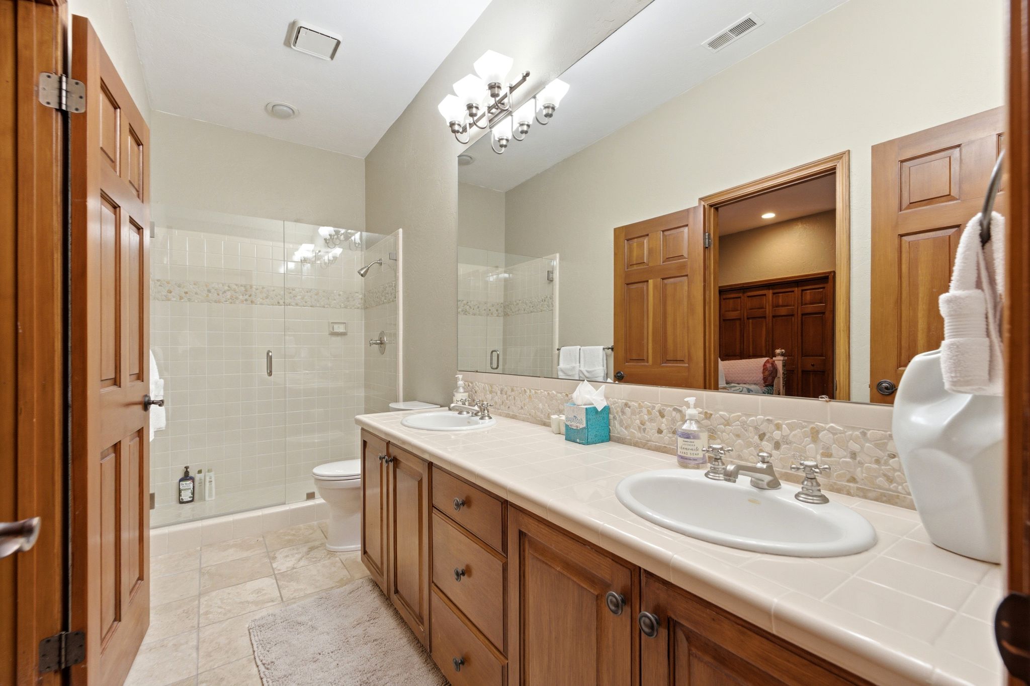 Double vanity with wood cabinetry, a light-toned countertop, and dual undermount sinks