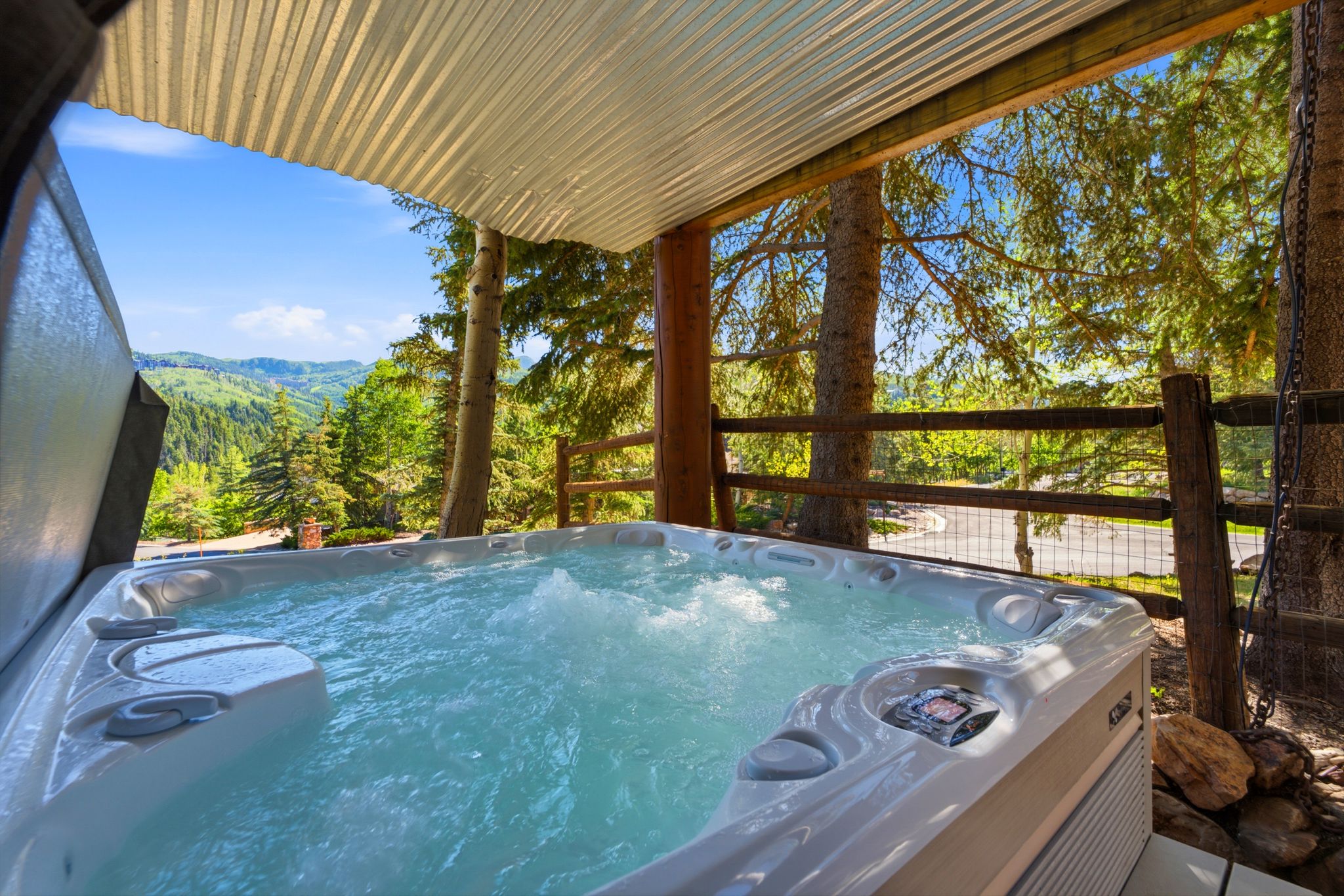 Outdoor spa with bubbling water, set on a covered deck featuring a corrugated metal ceiling