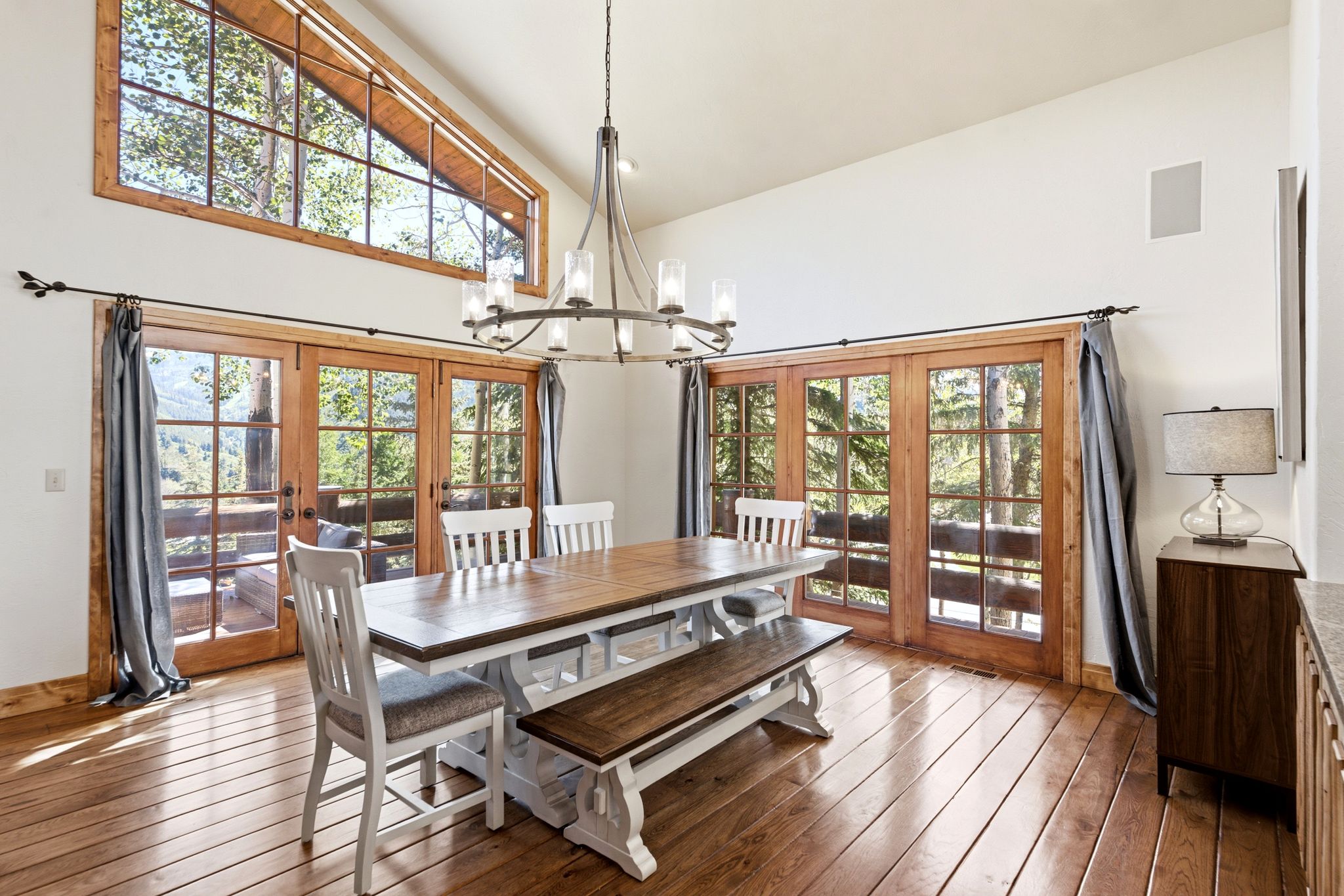 Open-concept dining area featuring vaulted ceilings, wood-finish flooring, and multiple sets of French doors with wood frames