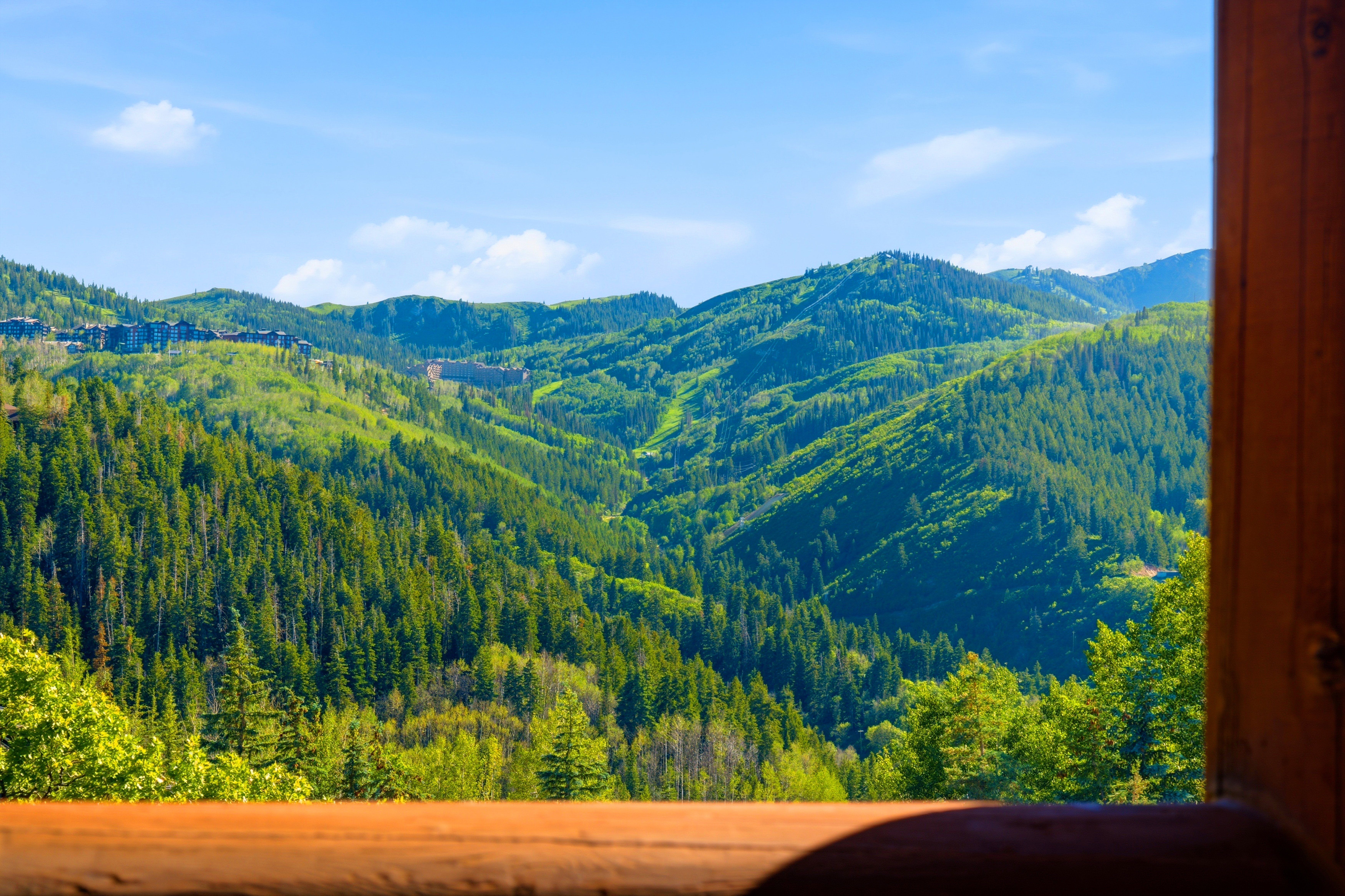Expansive mountain scenery framed by a rustic wood window
