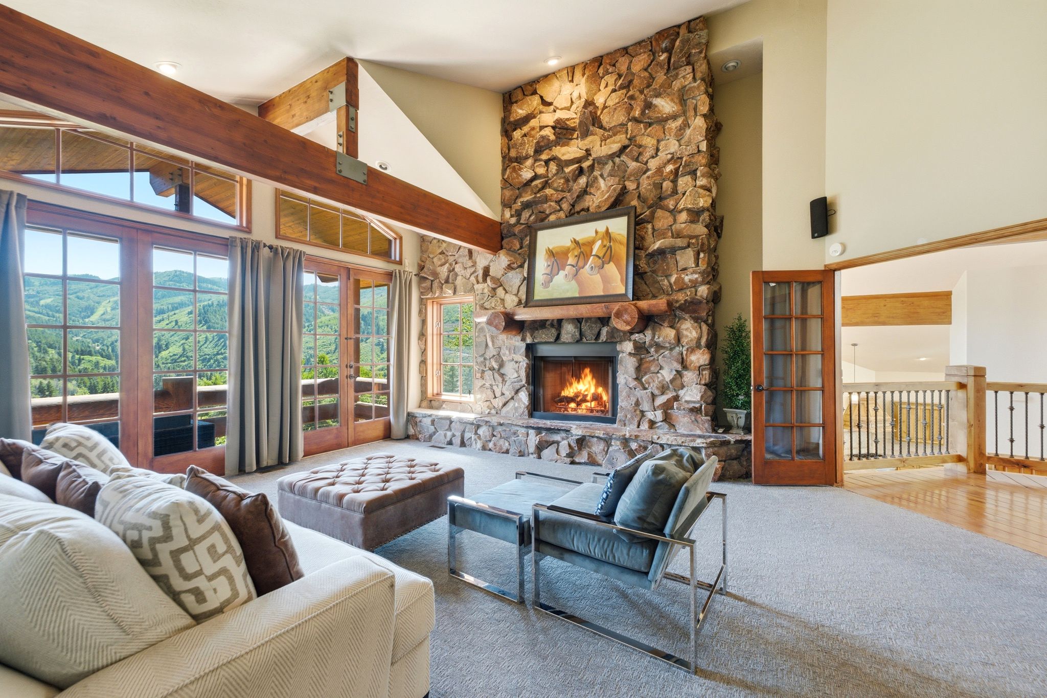 Vaulted living space with a floor-to-ceiling stone fireplace, exposed wood beams, and a wood mantel