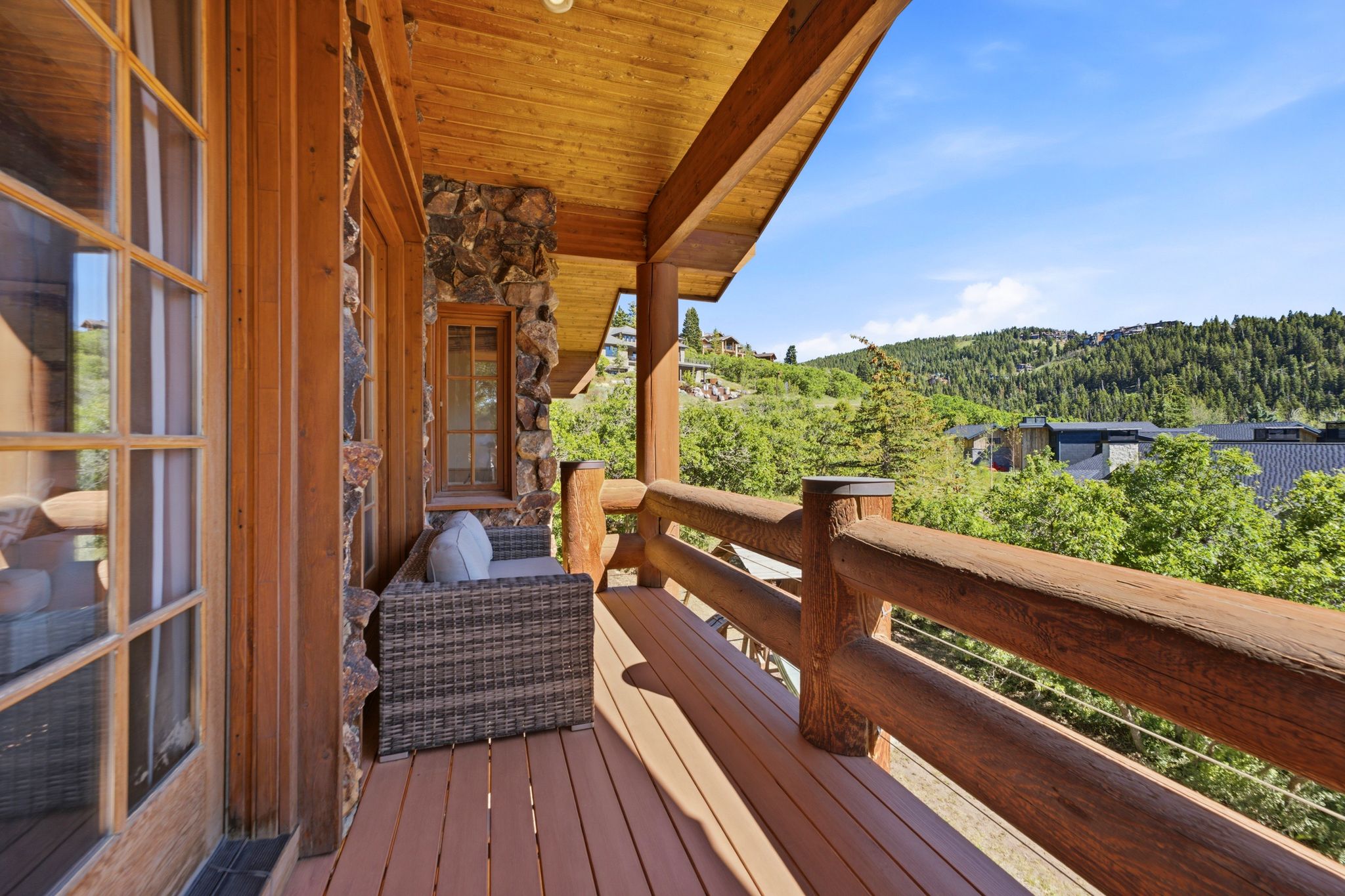 Expansive outdoor deck featuring wood-finish flooring, log railings, and a wood-paneled ceiling