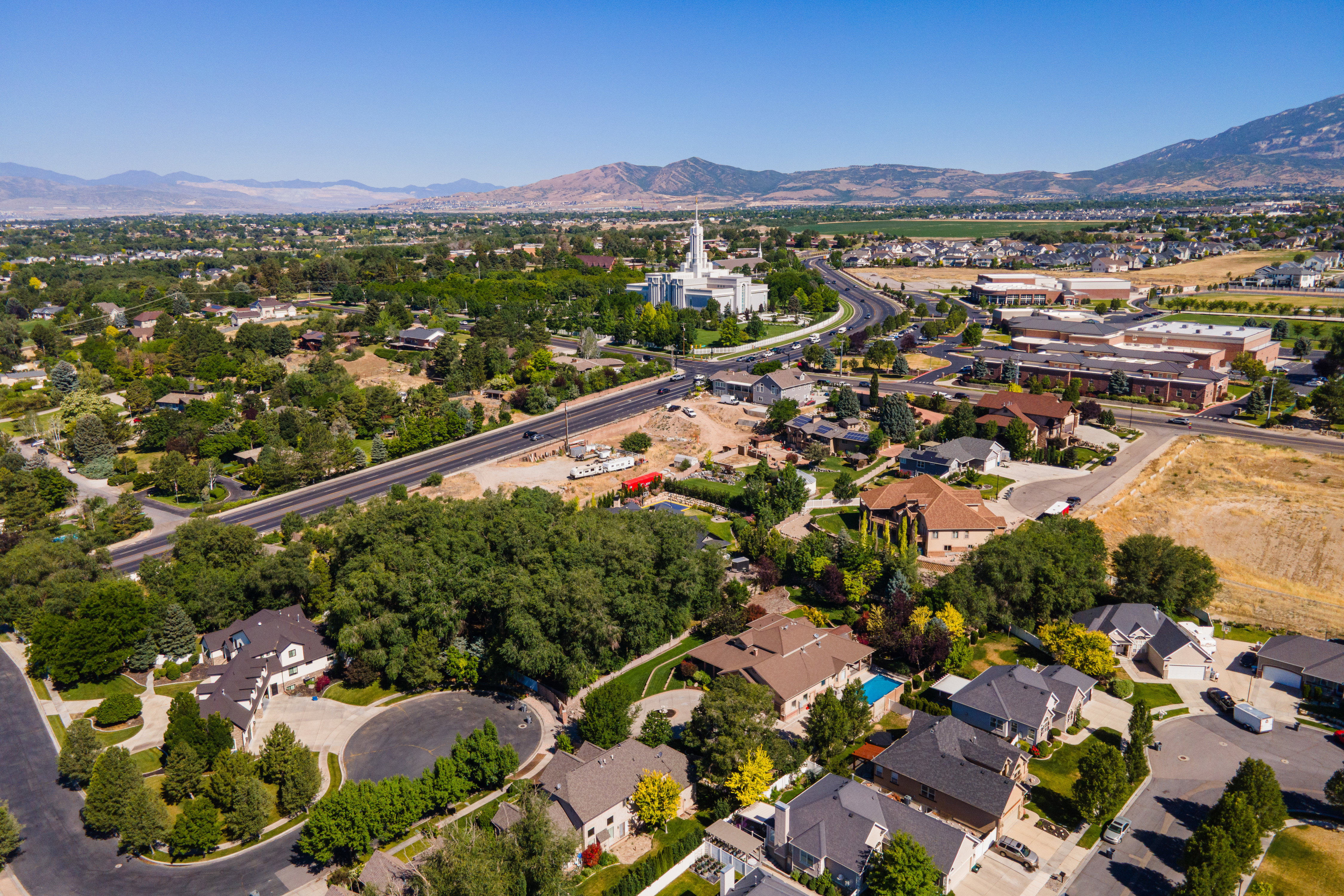Aerial perspective showcasing a residential area with varied housing styles, mature trees, and mountainous terrain