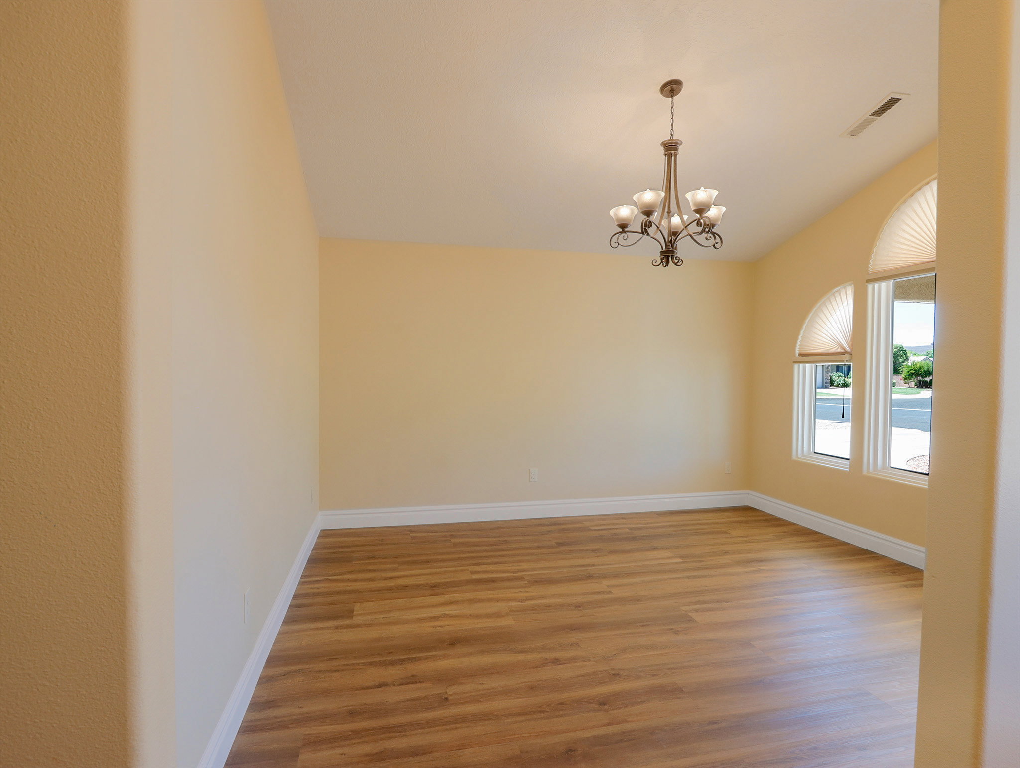 Spacious room featuring wood-finish flooring, high vaulted ceilings, and a decorative chandelier