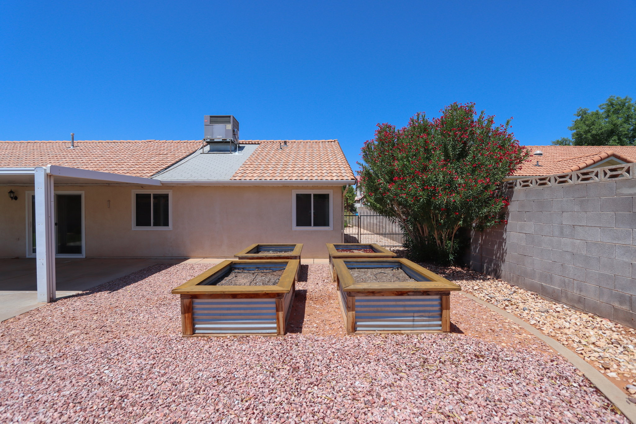 Spacious backyard featuring four raised garden beds with corrugated metal siding