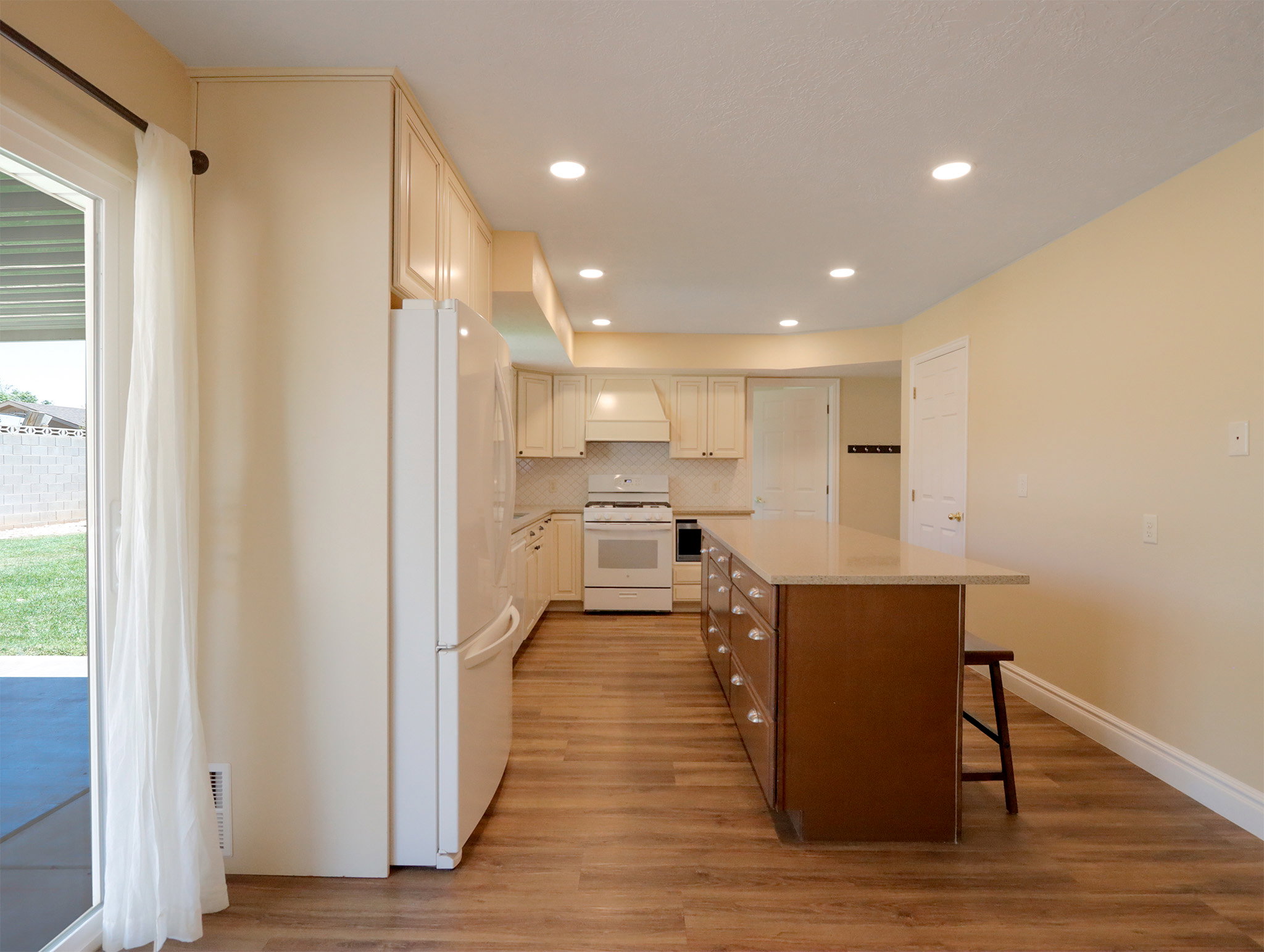 Kitchen featuring a central island with integrated storage, wood-finish flooring, recessed lighting, cream cabinetry, and a white tile backsplash
