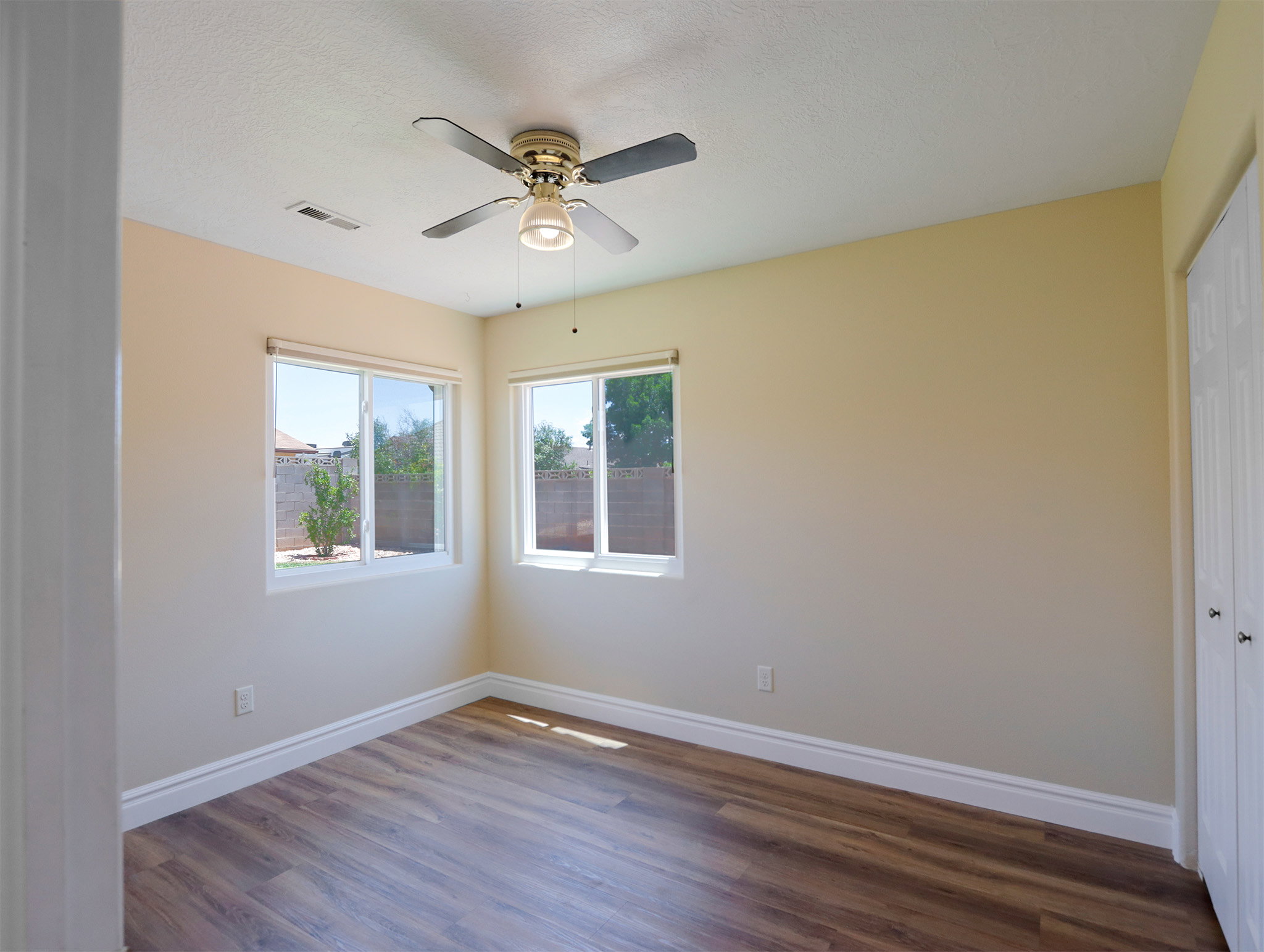 Well-lit interior space featuring wood-finish flooring, a ceiling fan, and multiple windows