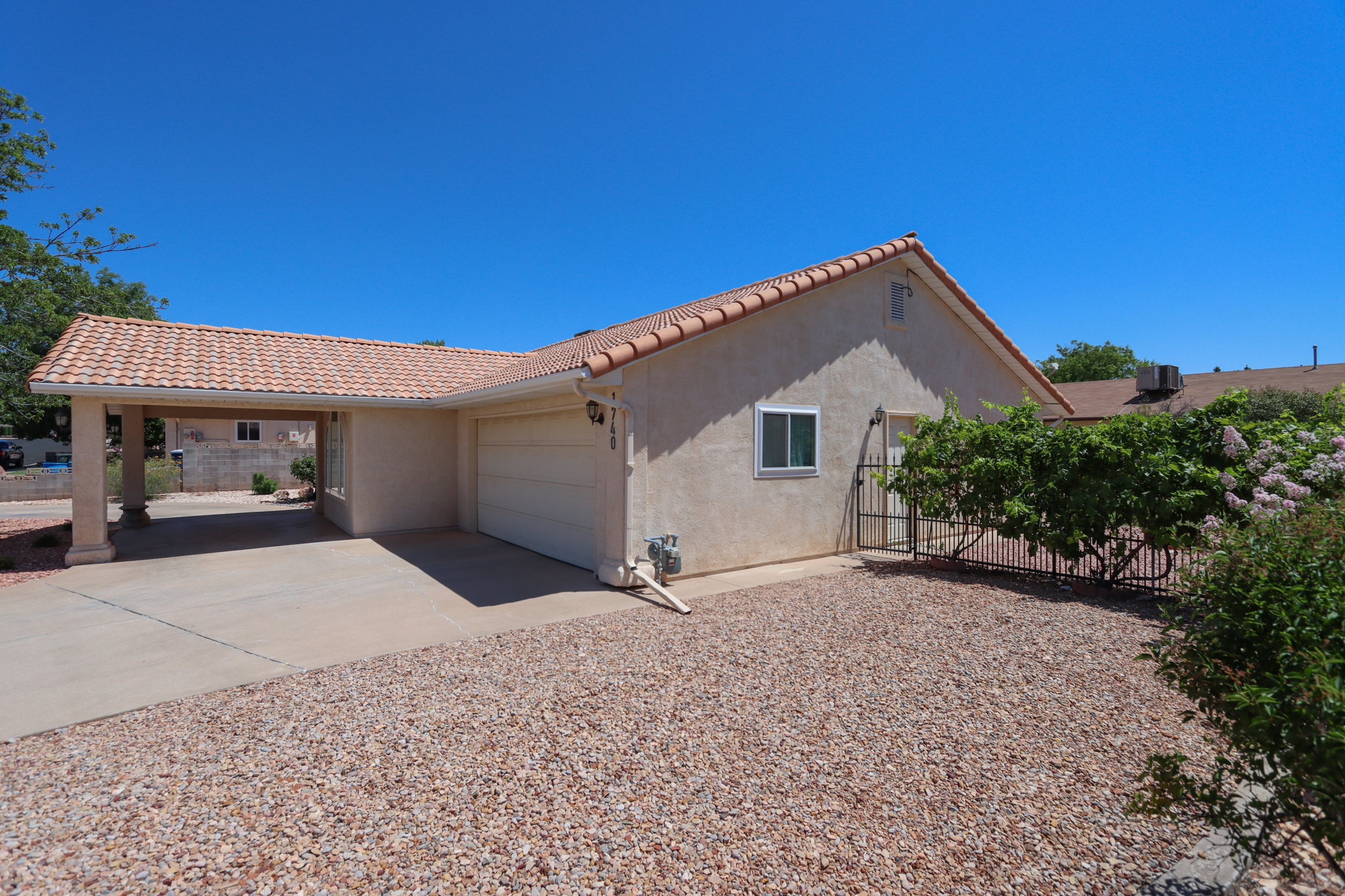 Stucco exterior with a tiled roof, featuring an attached carport and a single-car garage