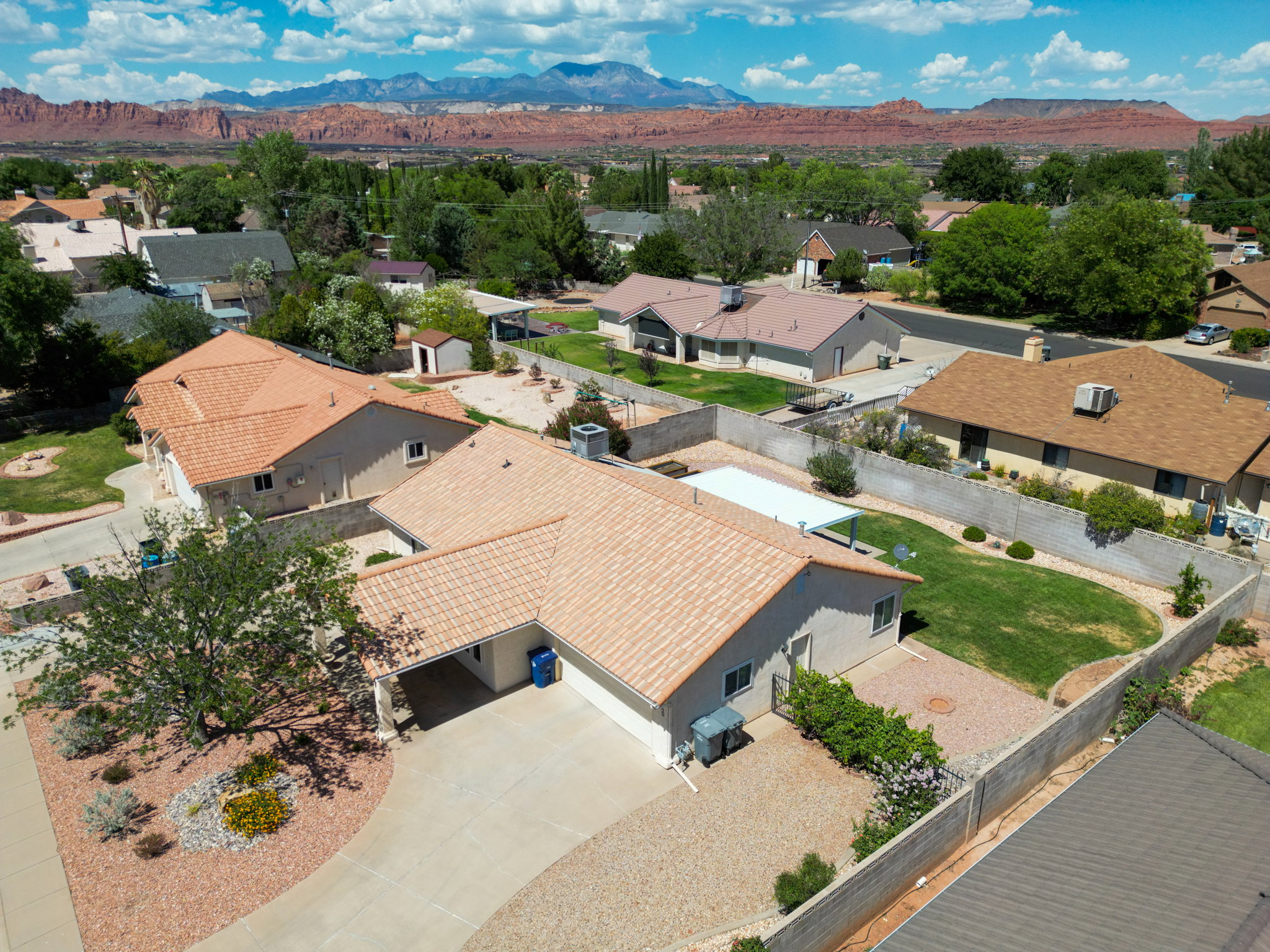 Aerial perspective showcasing a residential property with a tiled roof, an attached carport, and a paved driveway