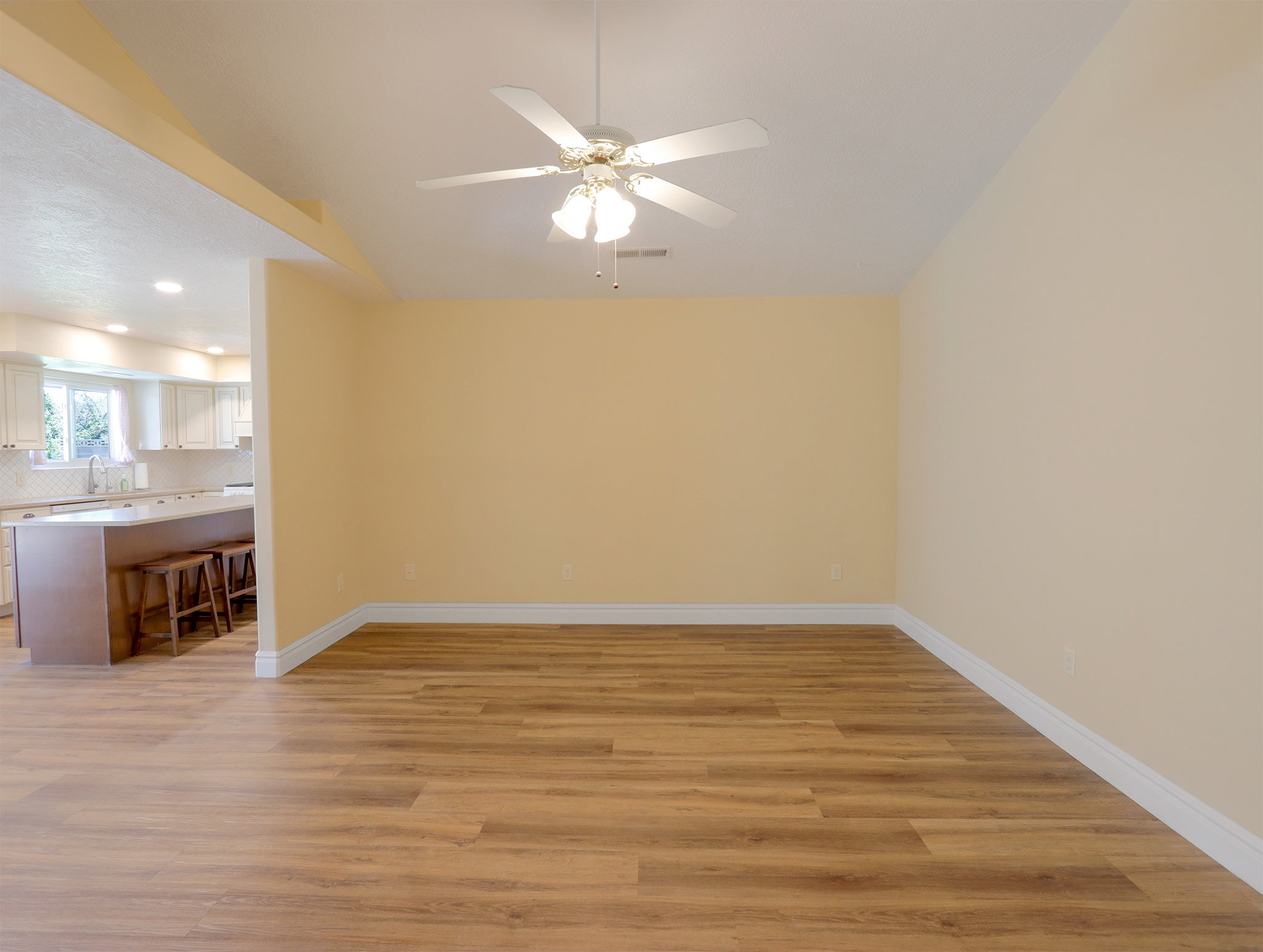 Spacious room featuring wood-finish flooring, light-toned walls, and a ceiling fan