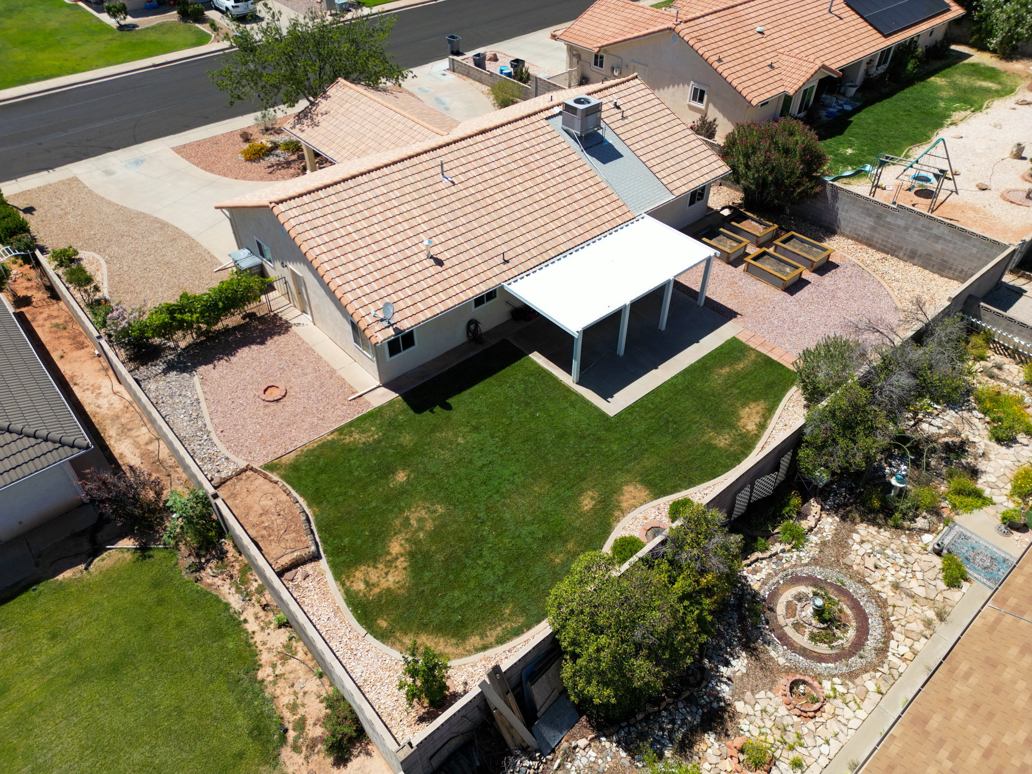 Rear exterior with a covered patio, expansive lawn, and gravel landscaping