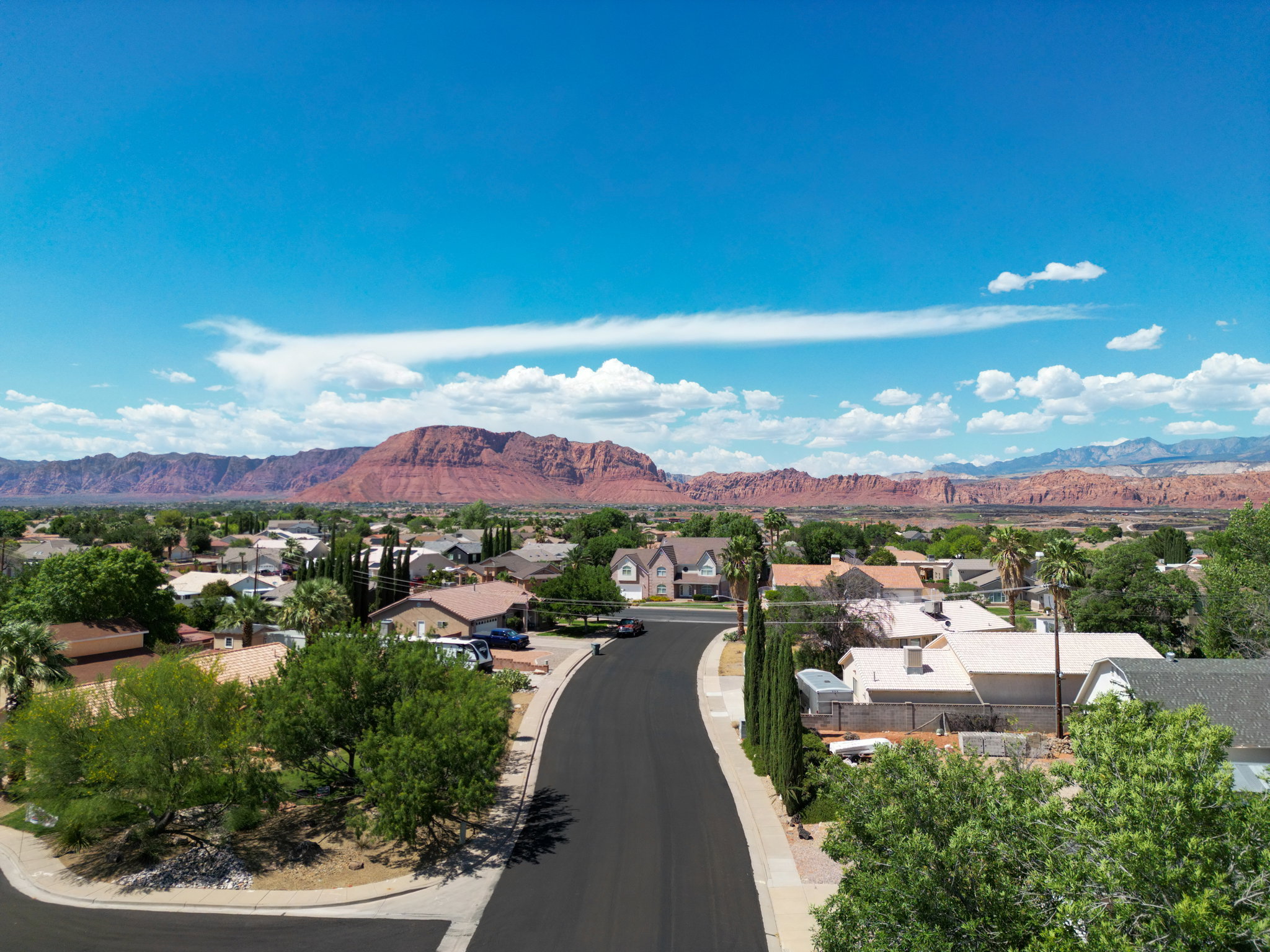 Neighborhood setting with a street, residential properties, and distant red rock formations