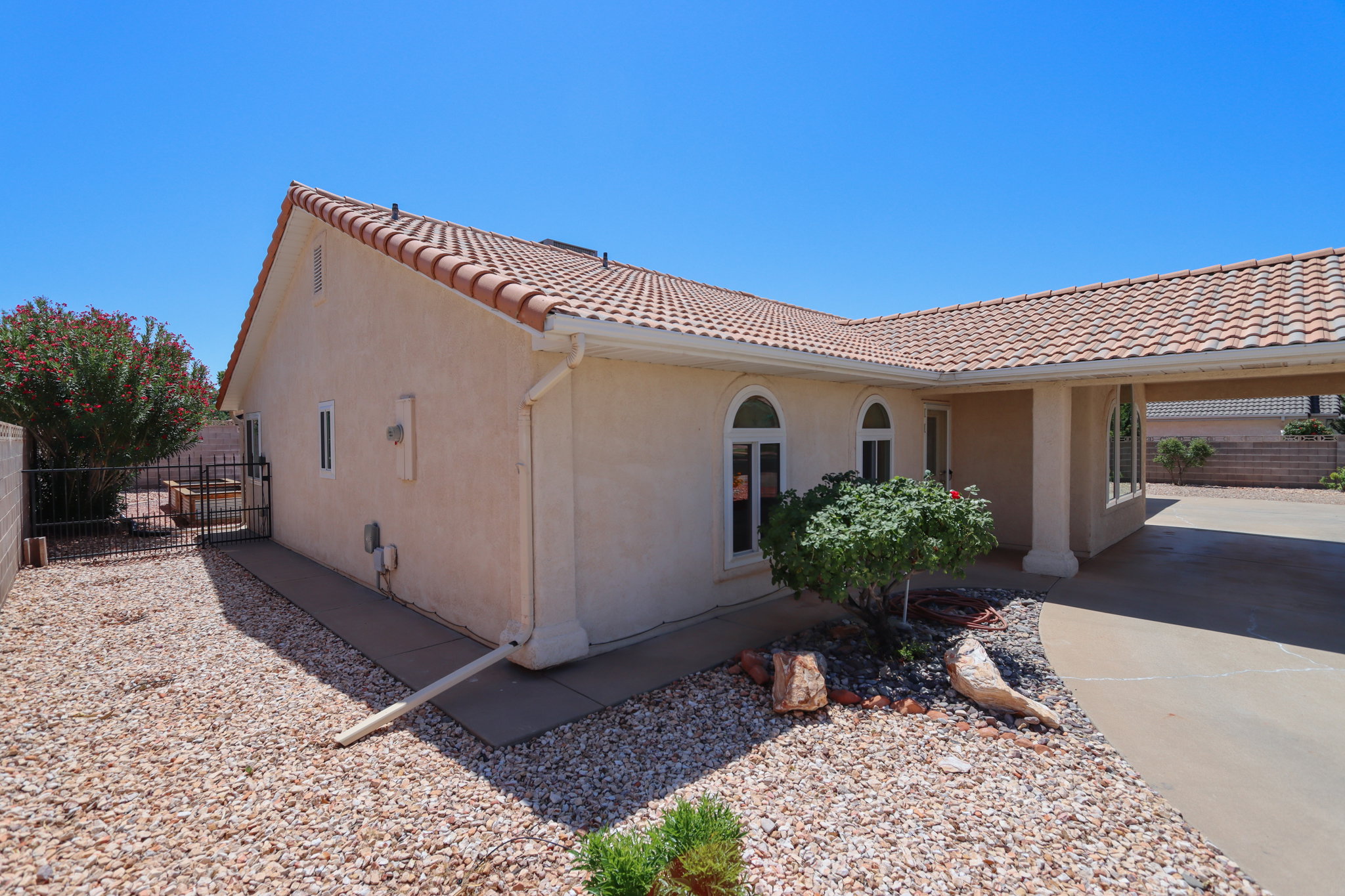 Stucco exterior featuring a red tile roof and arched windows