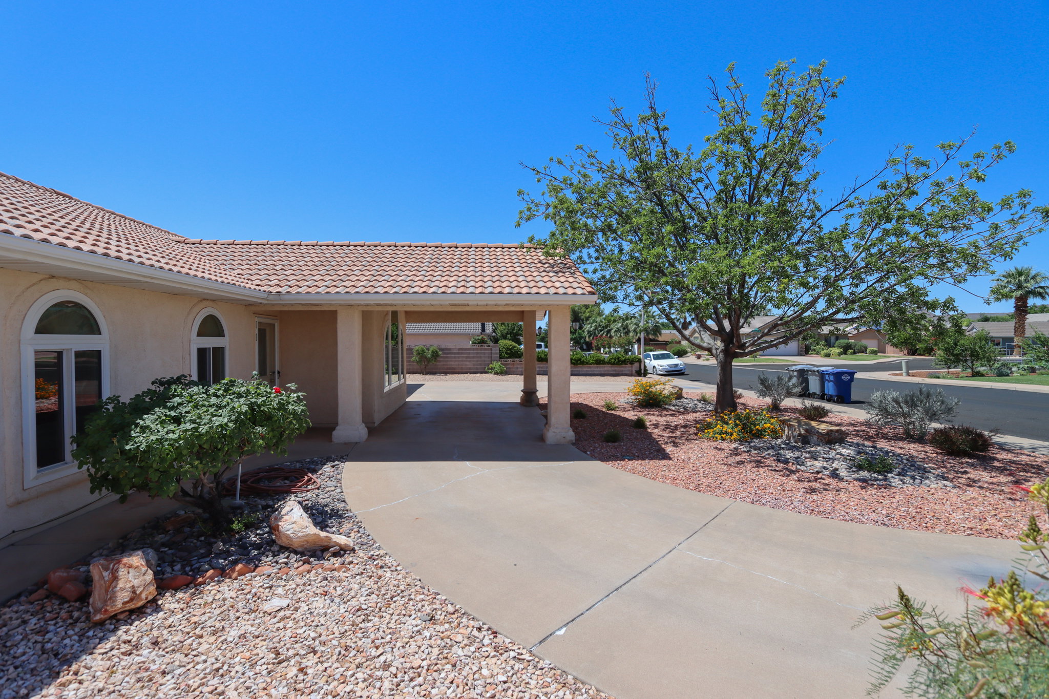 Front exterior featuring a covered portico, stucco finish, arched windows, and a tile roof