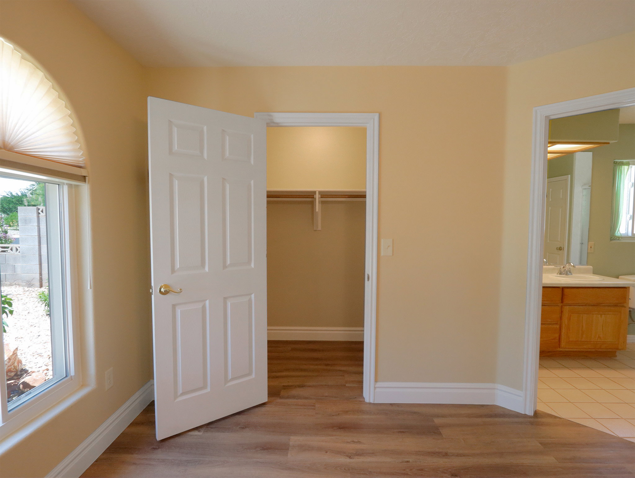 Warm-toned walls with contrasting white trim, wood-finish flooring, a built-in closet with shelving, and a six-panel interior door