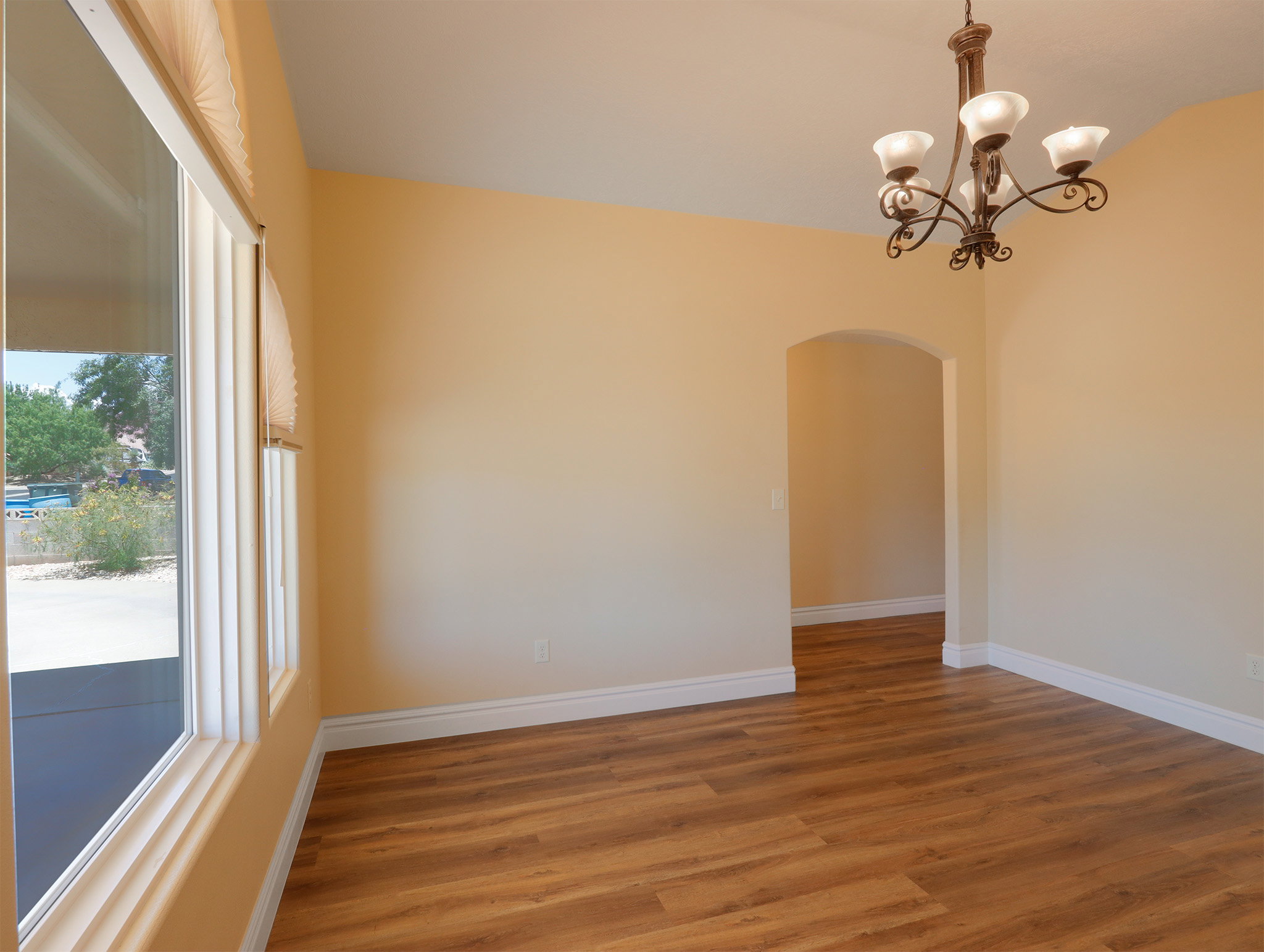 Spacious interior featuring wood-finish flooring, an arched doorway, and a traditional wrought-iron chandelier