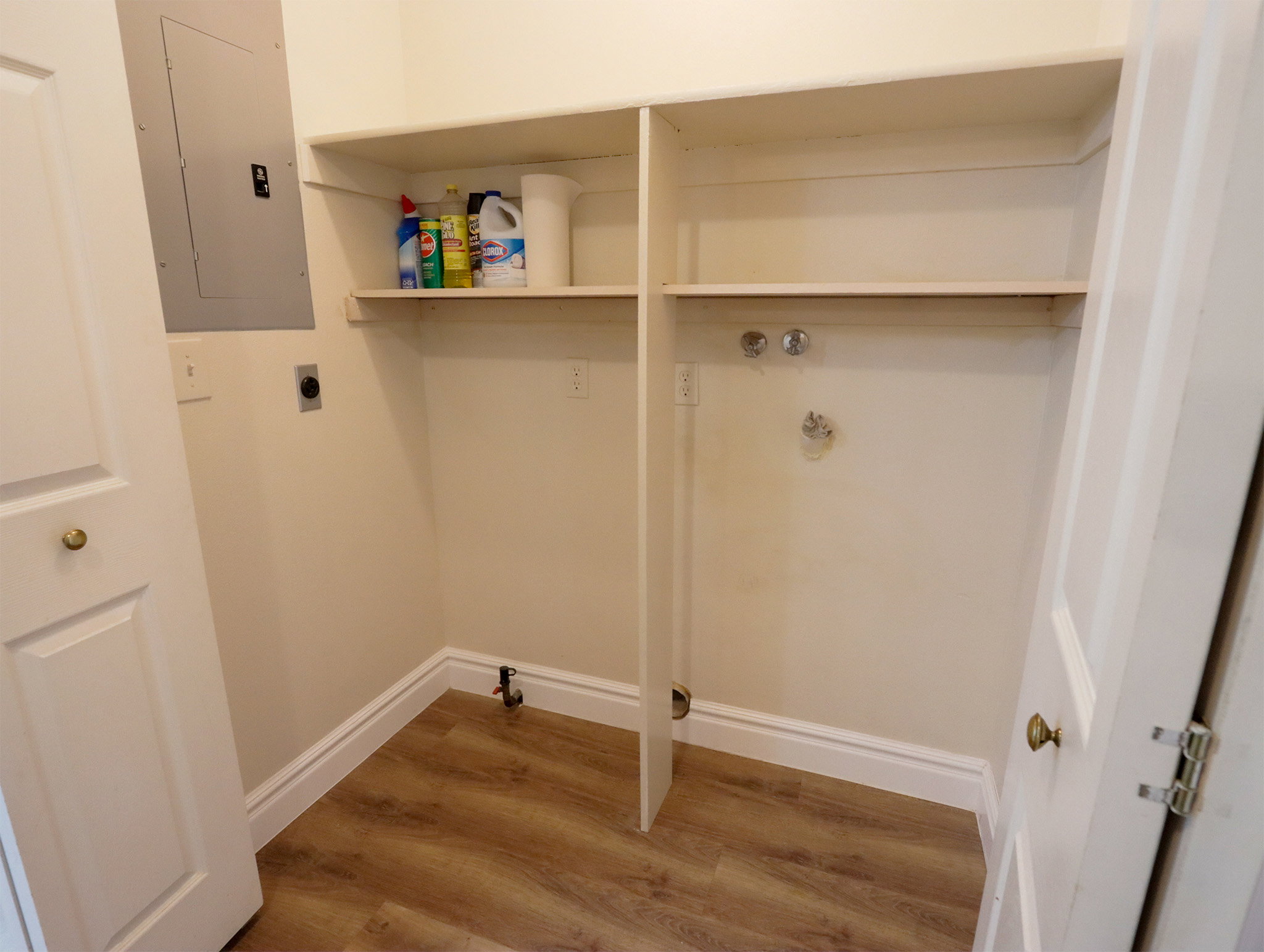 Dedicated laundry area featuring wood-finish flooring, built-in shelving, and utility hookups