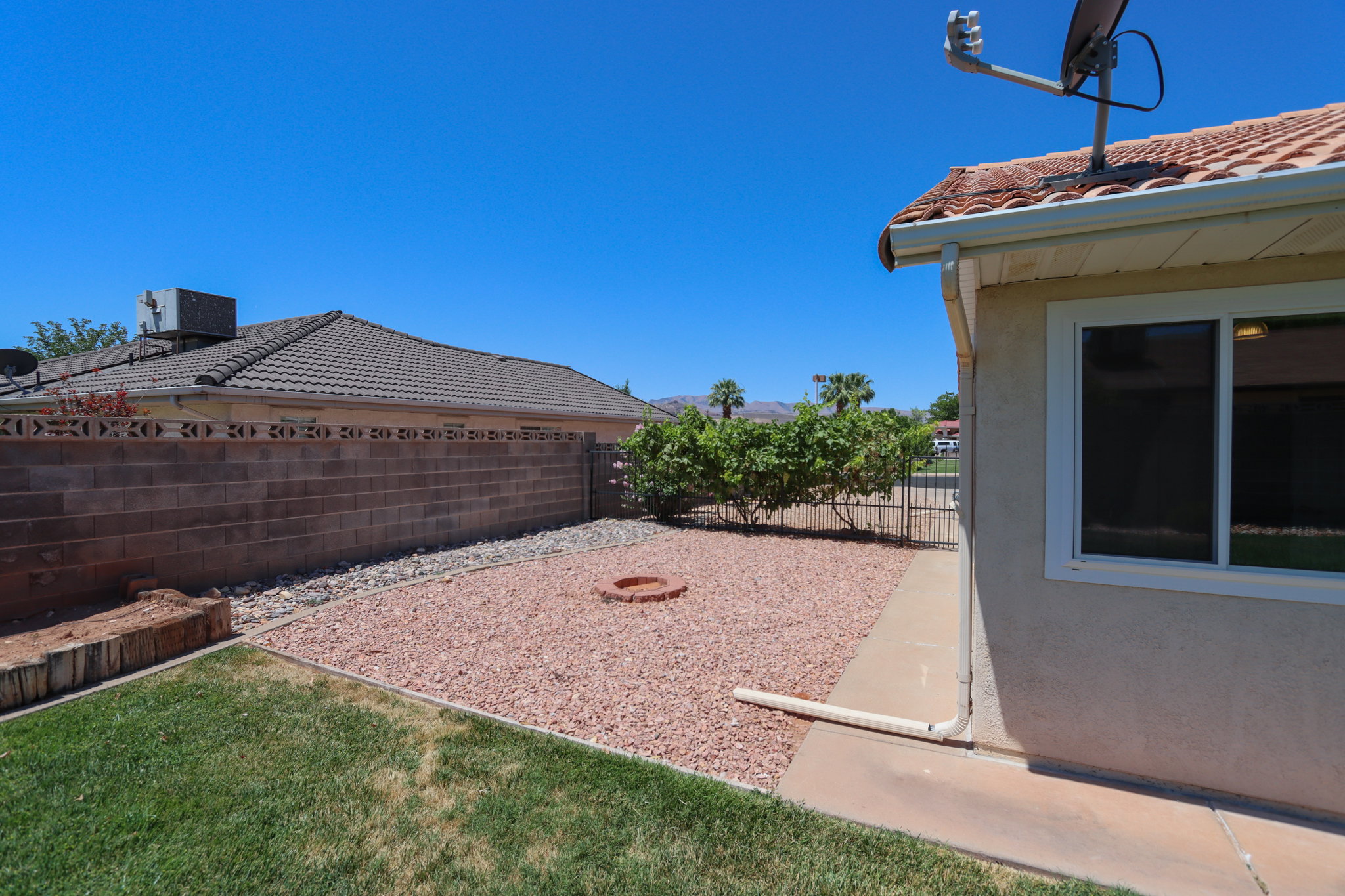 Backyard featuring a combination of turf, gravel, and concrete paving