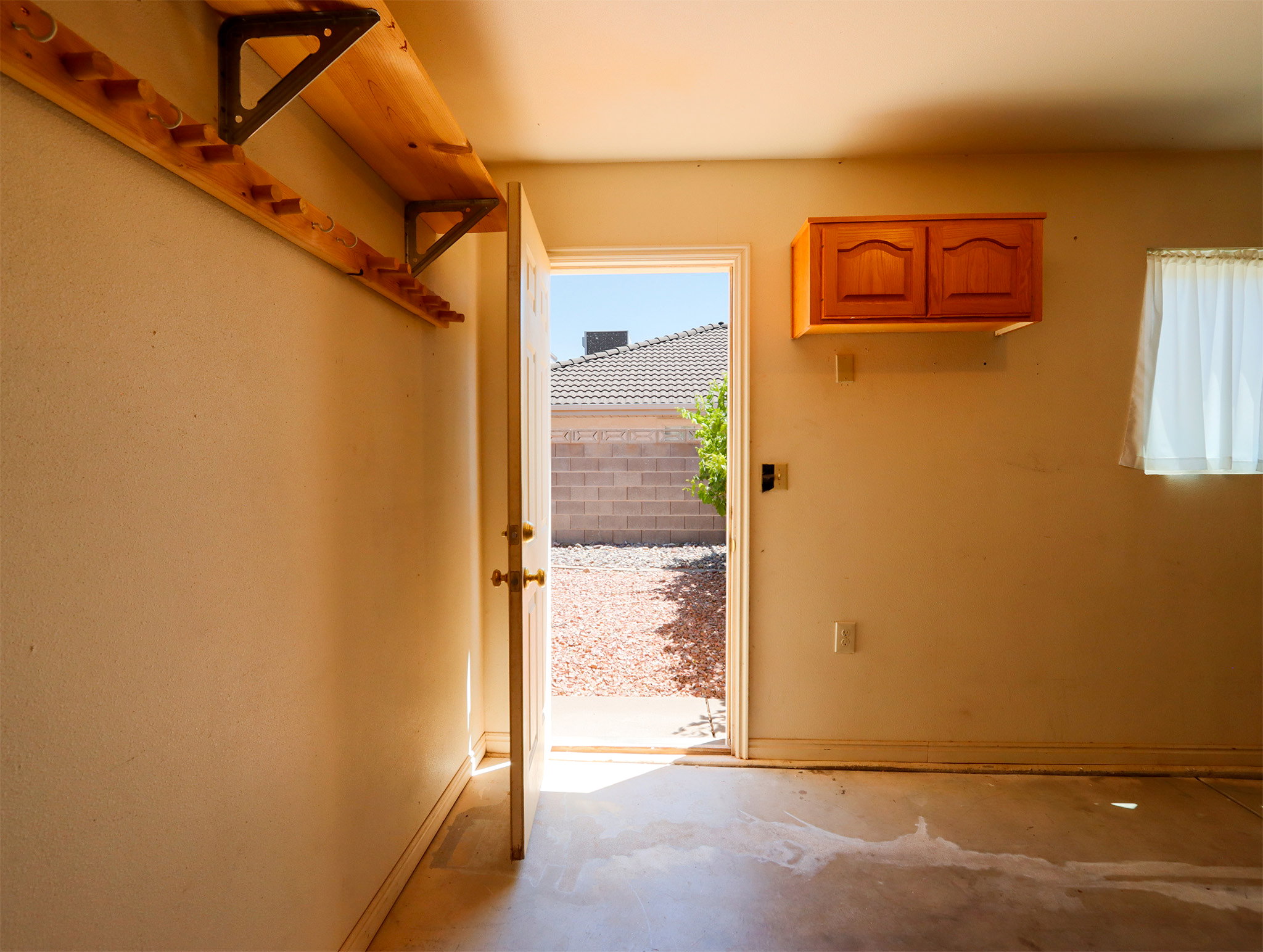 Garage interior featuring a light-toned wall finish, built-in wooden shelving with metal brackets, and an overhead wooden cabinet