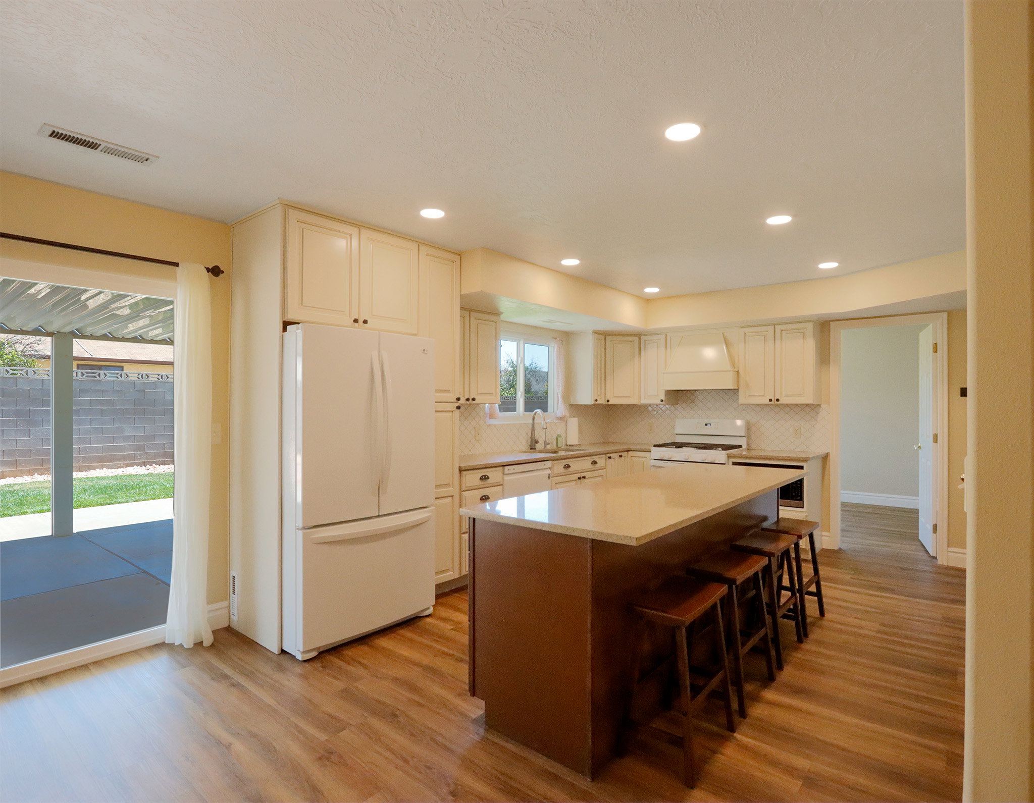Kitchen featuring an expansive island with a light-toned countertop, wood-finish flooring, recessed lighting, and cream cabinetry