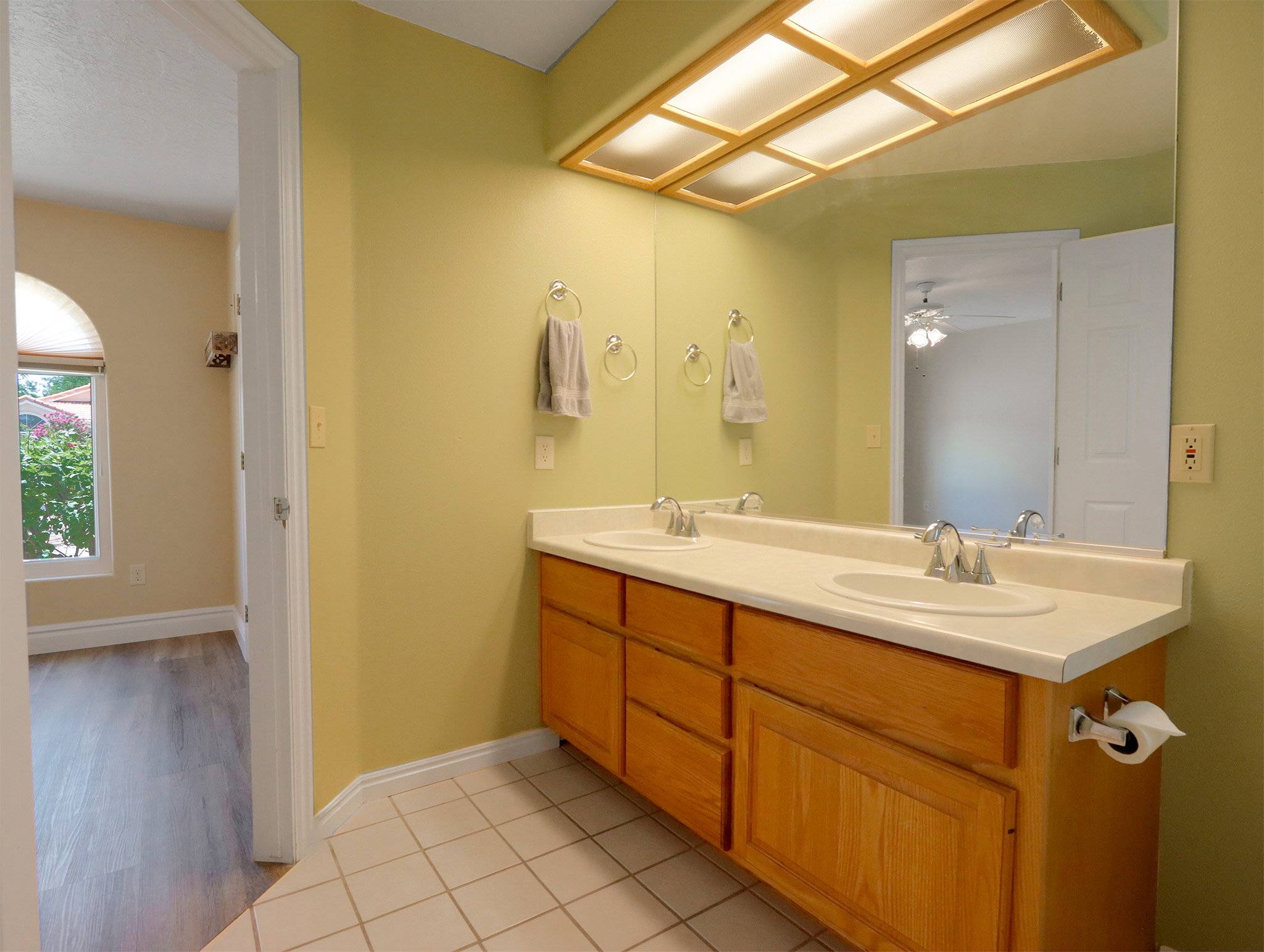 Bathroom featuring a dual vanity with light wood cabinetry and integrated sinks