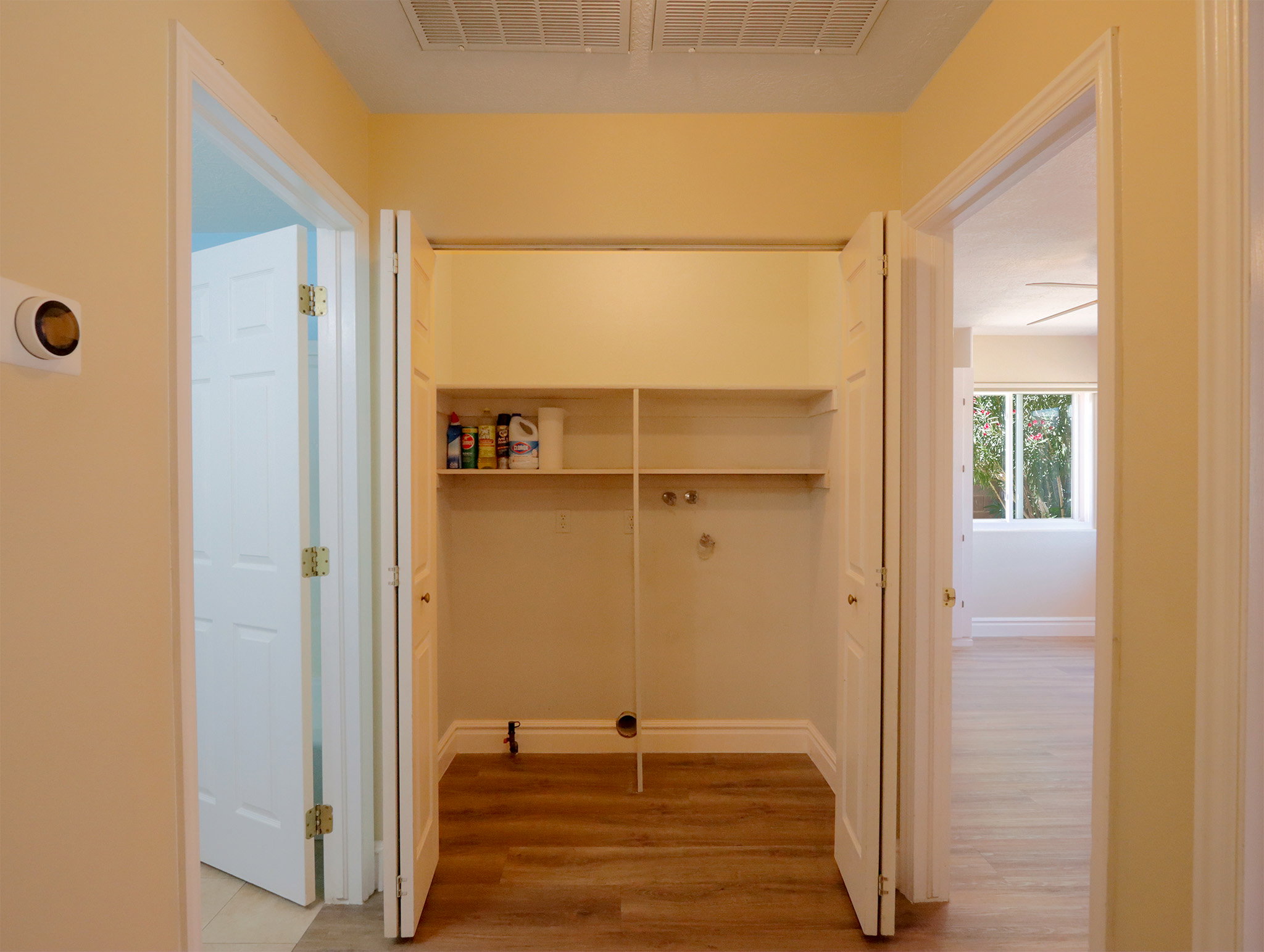 Dedicated laundry closet featuring wood-finish flooring, built-in shelving, and utility hookups