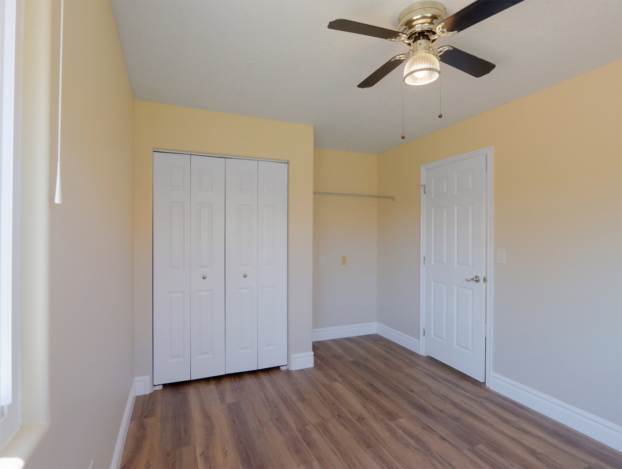Room featuring wood-finish flooring, light-toned wall paint, and white trim
