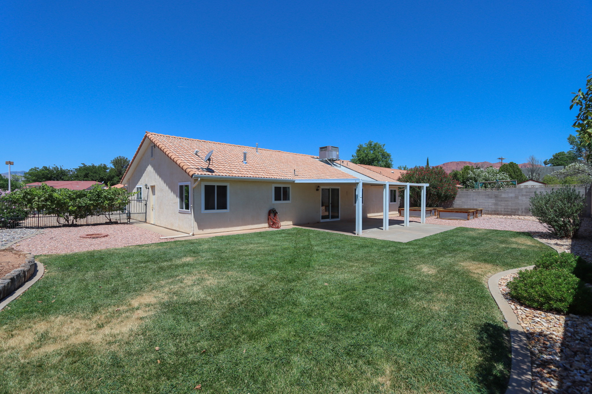 Expansive backyard featuring a covered patio, turf lawn, and gravel landscaping