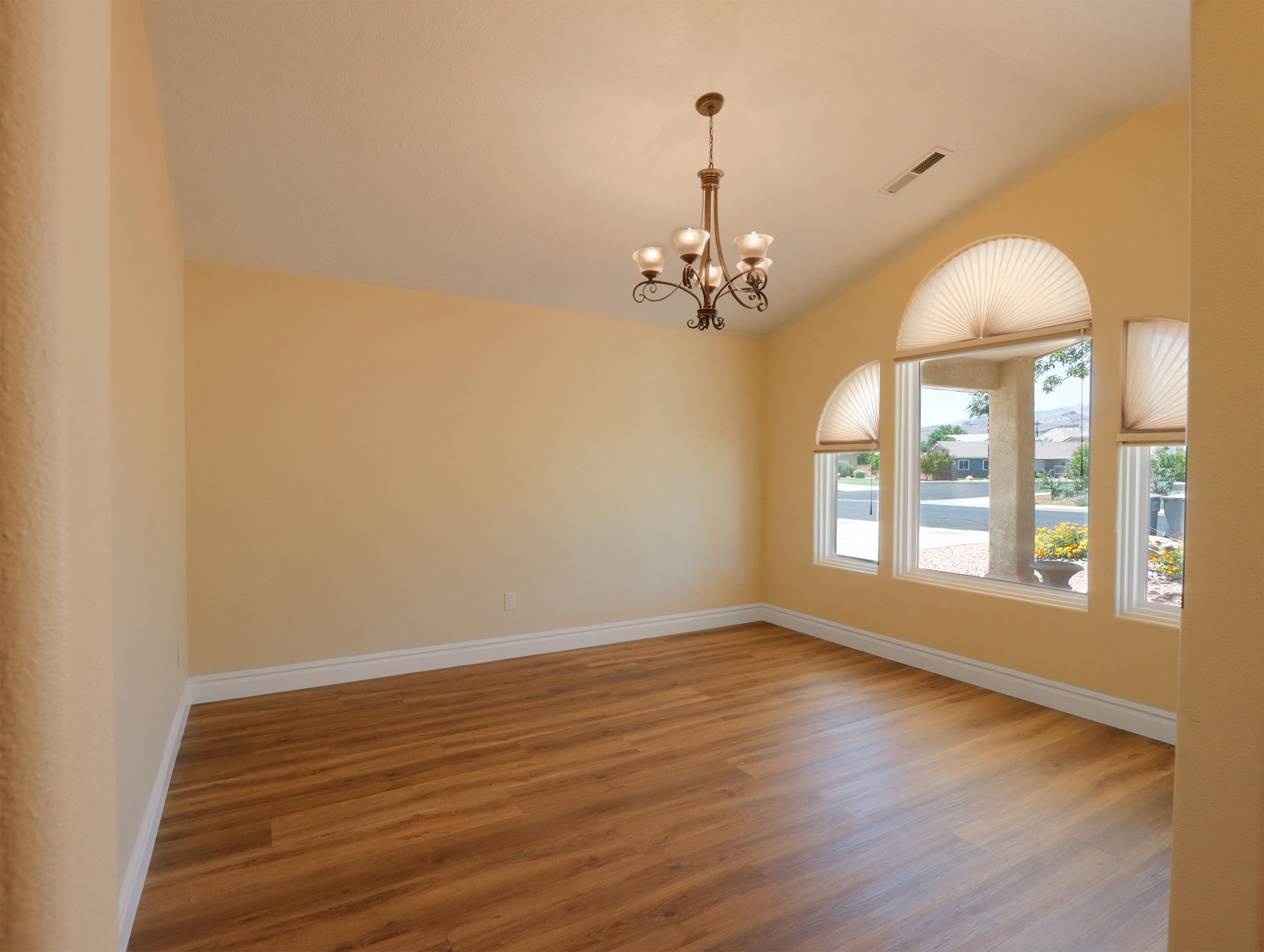 Spacious room featuring wood-finish flooring, vaulted ceilings, and a bronze chandelier