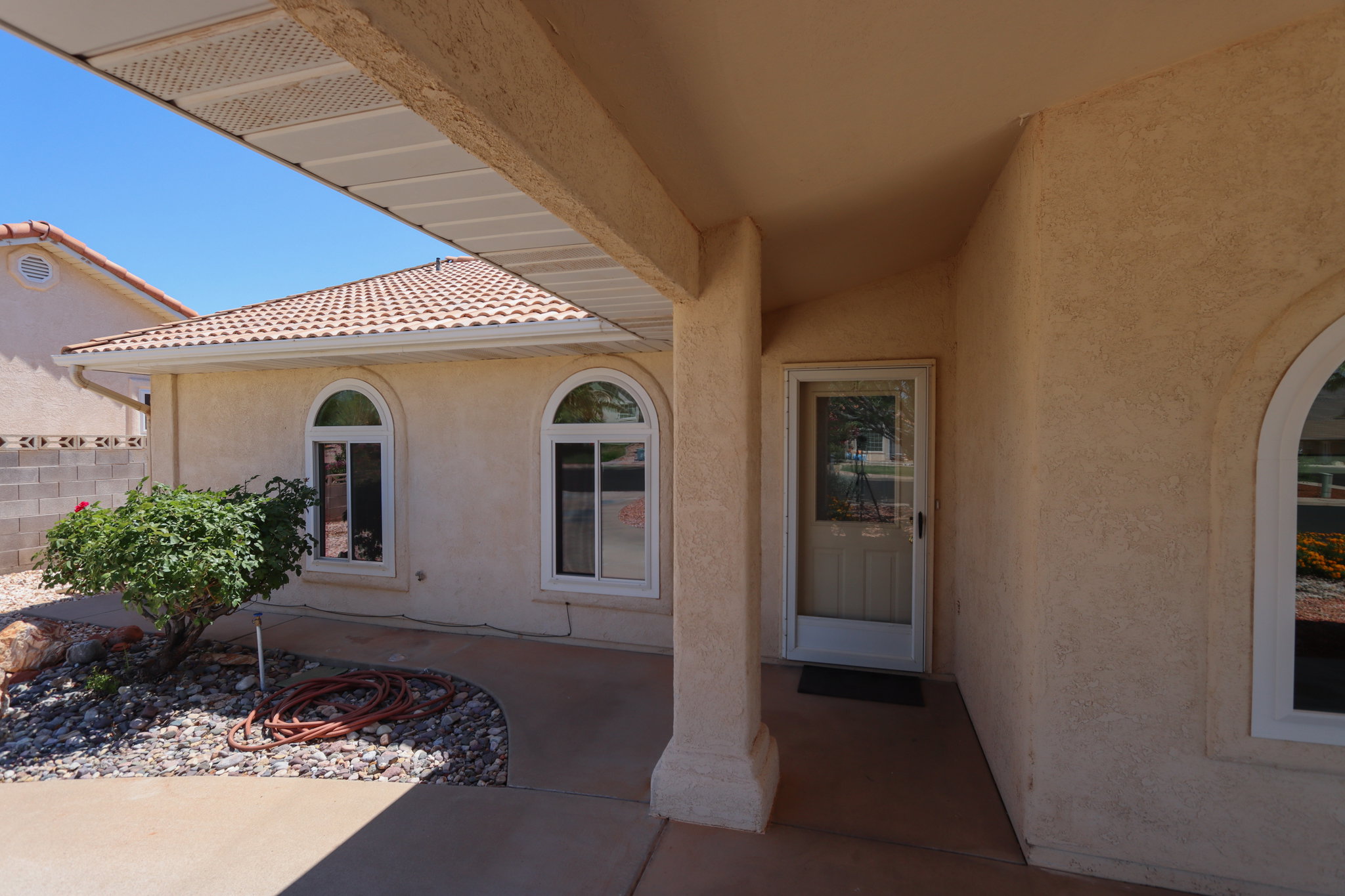 Stucco exterior featuring an arched entryway with a screen door and decorative glass inserts